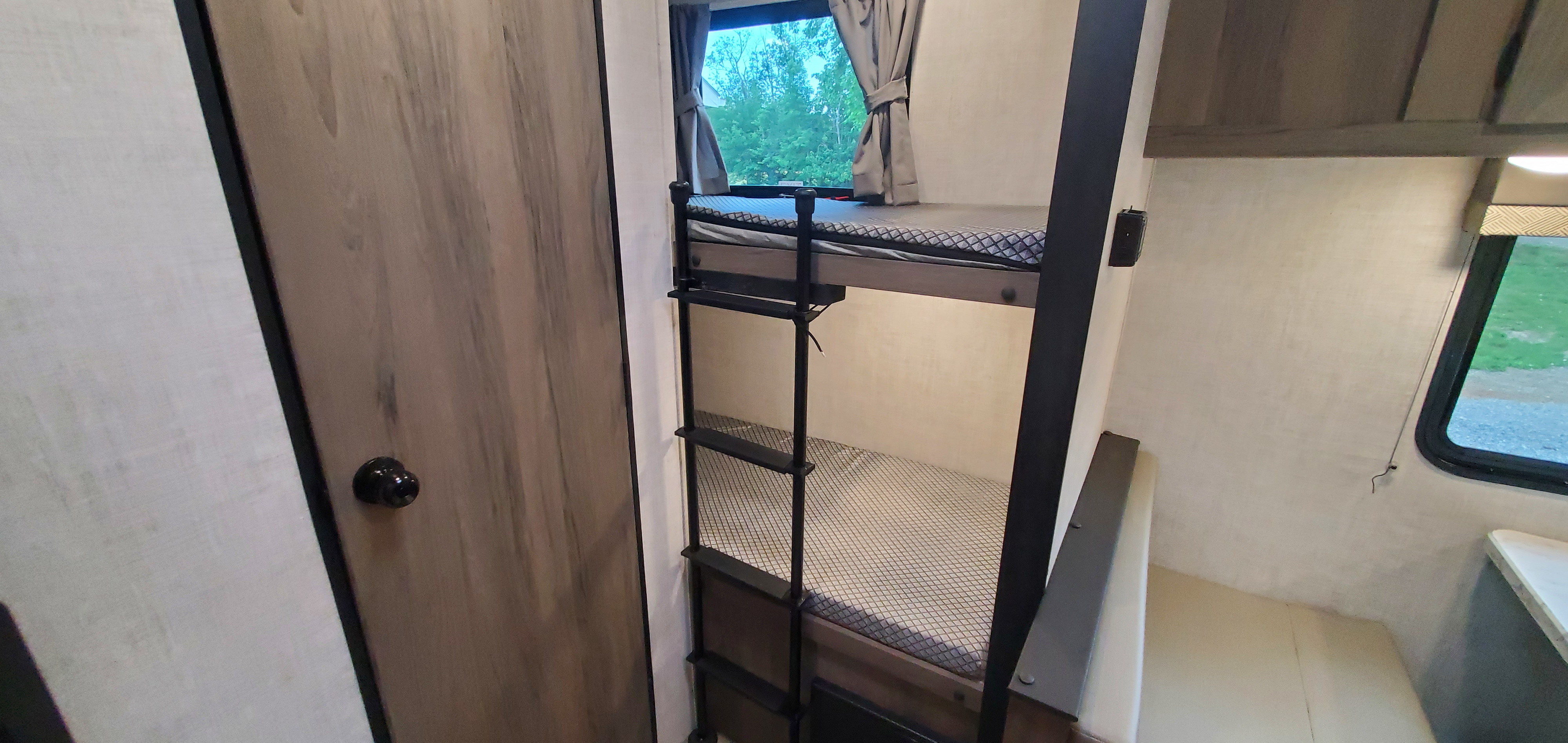 RV rental interior: bunk beds with ladder, window, and comfortable sleeping space in a travel trailer.. Gulf Stream Trailmaster 2022