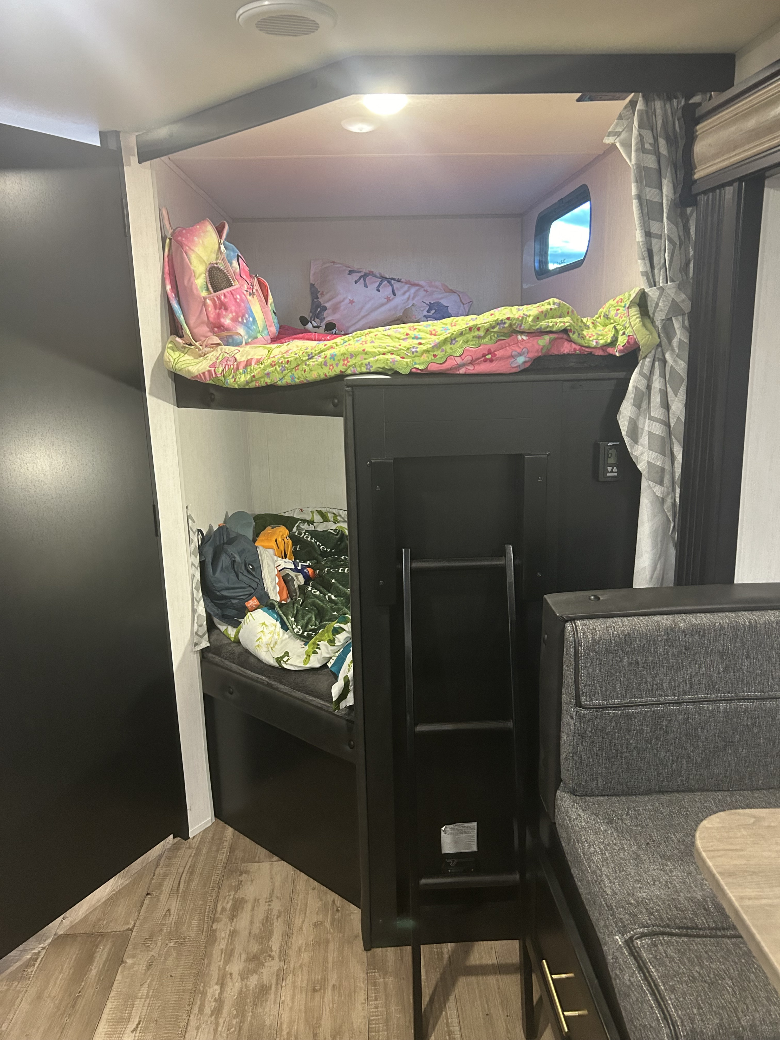 An RV rental interior features cozy bunk beds with bedding, a ladder, and an adjacent dinette seating area.. Forest River Cherokee Grey Wolf 2022