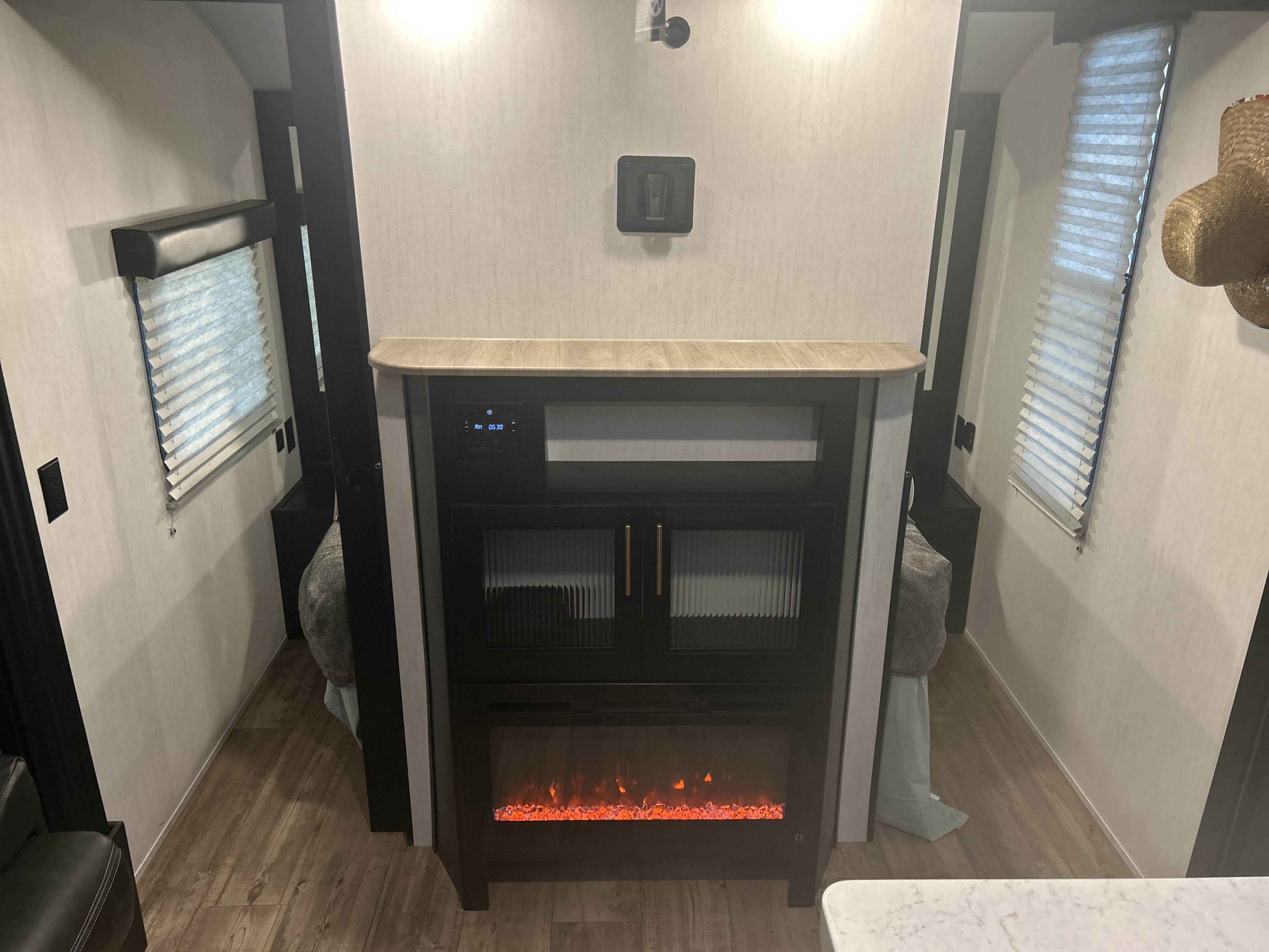 Cozy RV rental bedroom with a central entertainment unit, electric fireplace, and blinds on both side windows.. Forest River Cherokee Grey Wolf 2022