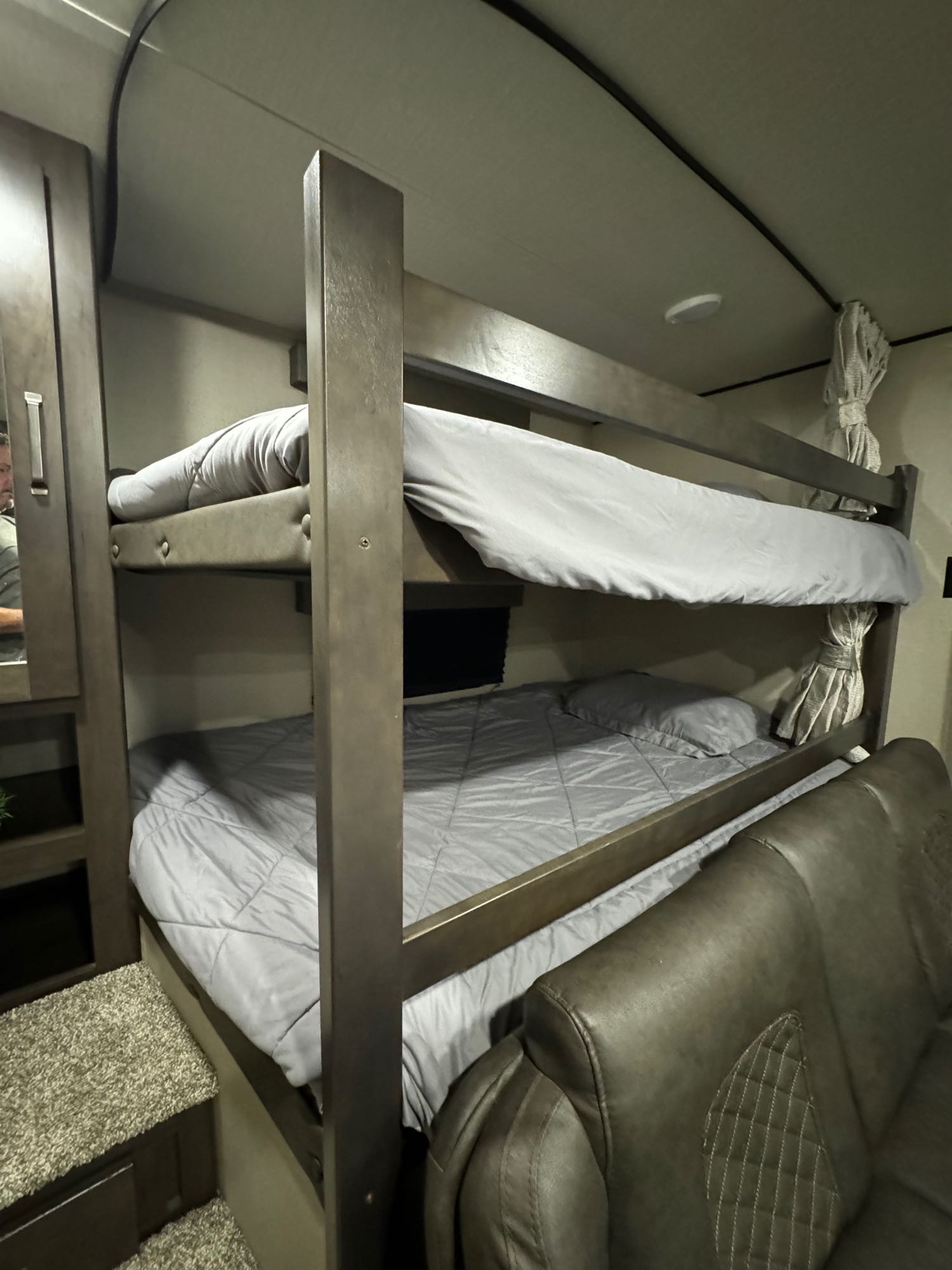 Cozy RV rental interior featuring bunk beds with light gray bedding and a comfy sofa.. Grand Design Transcend Xplor 2022