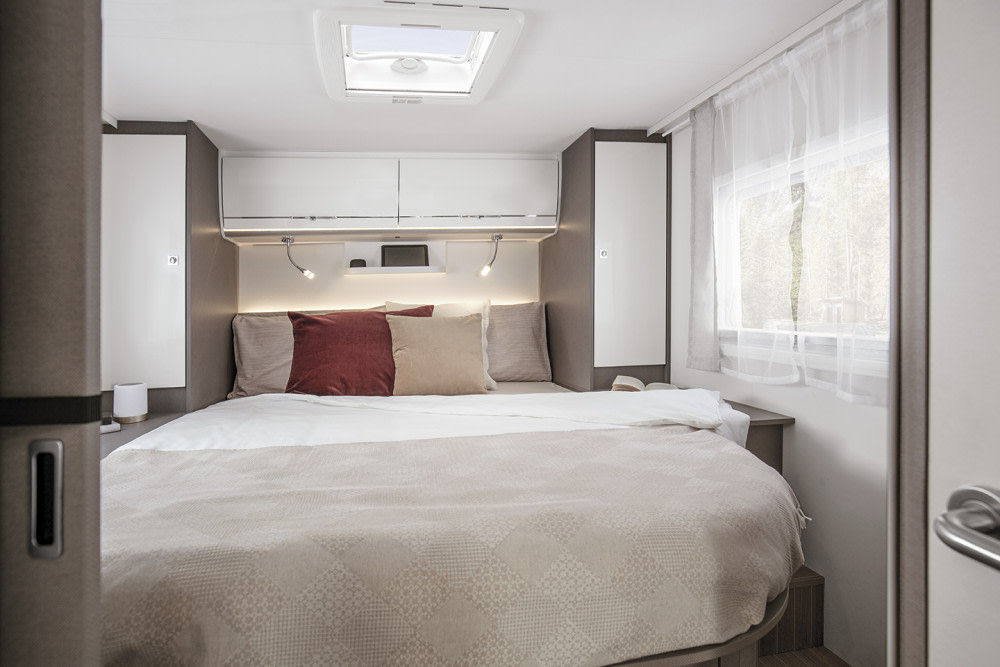 Step inside this RV rental's modern bedroom, featuring a large bed, overhead storage, reading lights, and a bright skylight.. Etrusco Etrusco I7400QBC 2024