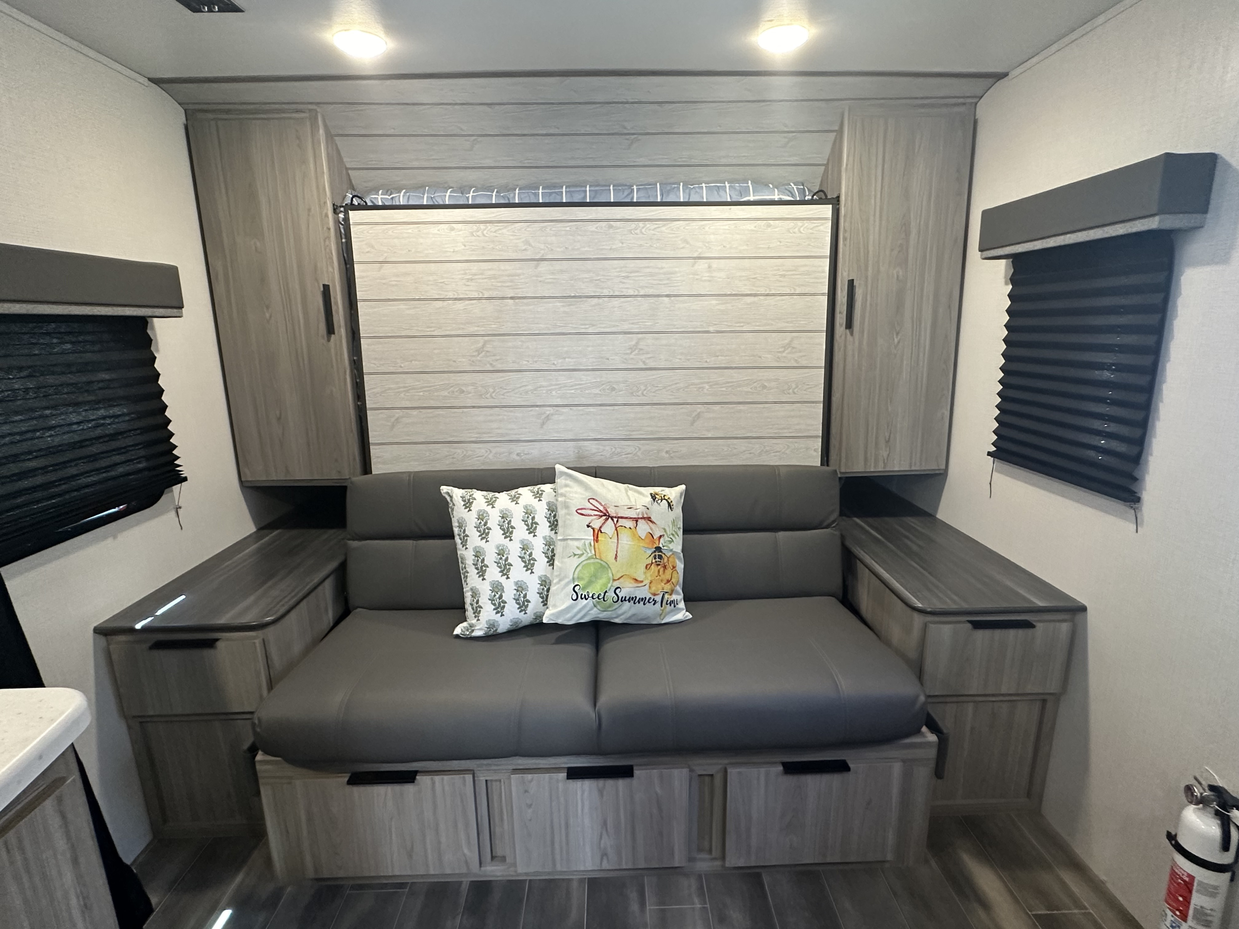RV rental interior: gray sofa converts to a bed, with a hidden wall bed above & integrated storage units.. Keystone RV Passport SL 2022