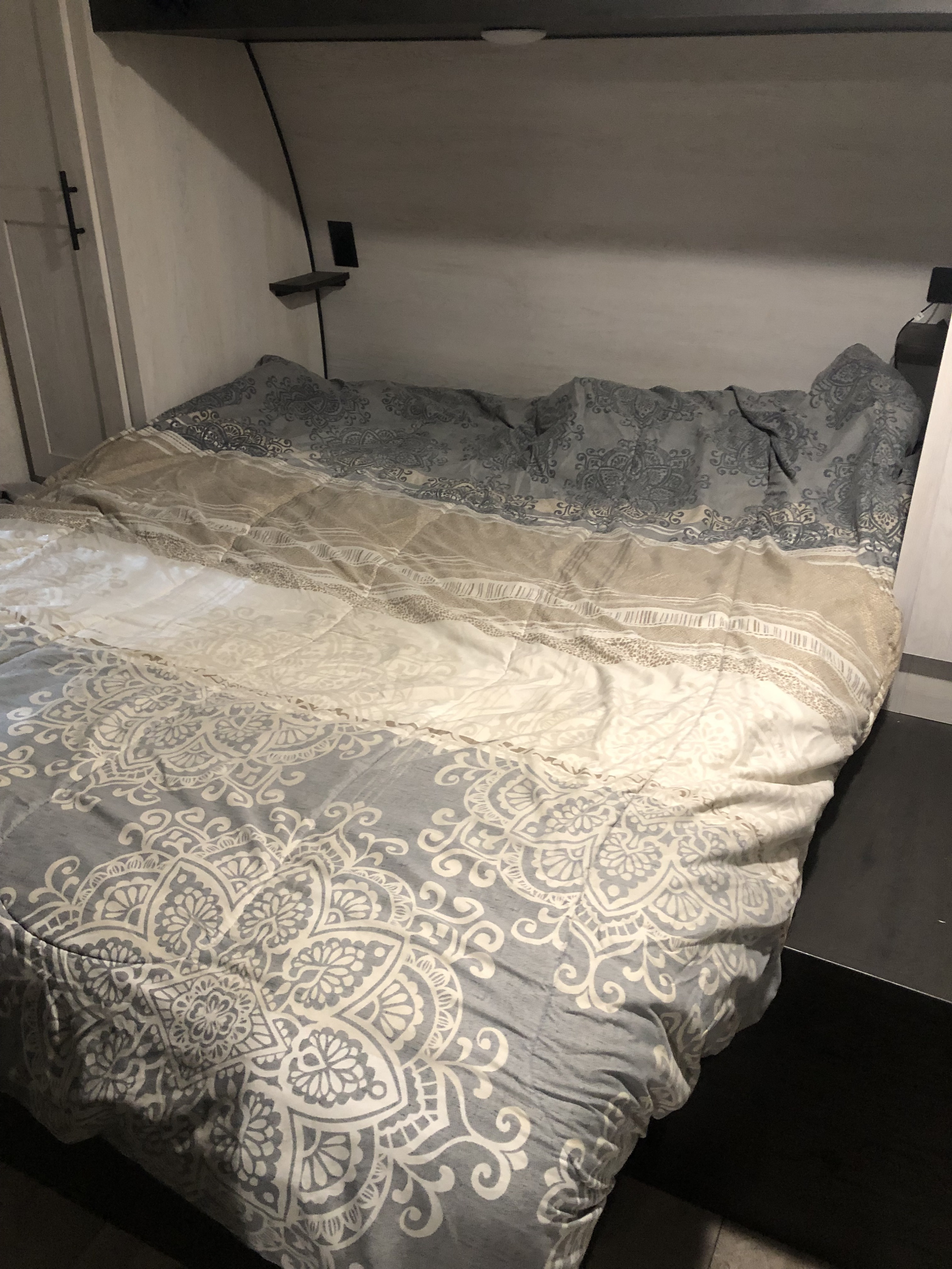 RV rental bedroom with a cozy bed and a patterned gray, white, and beige comforter, showing the compact interior.. KZ Sportsman SE 2022