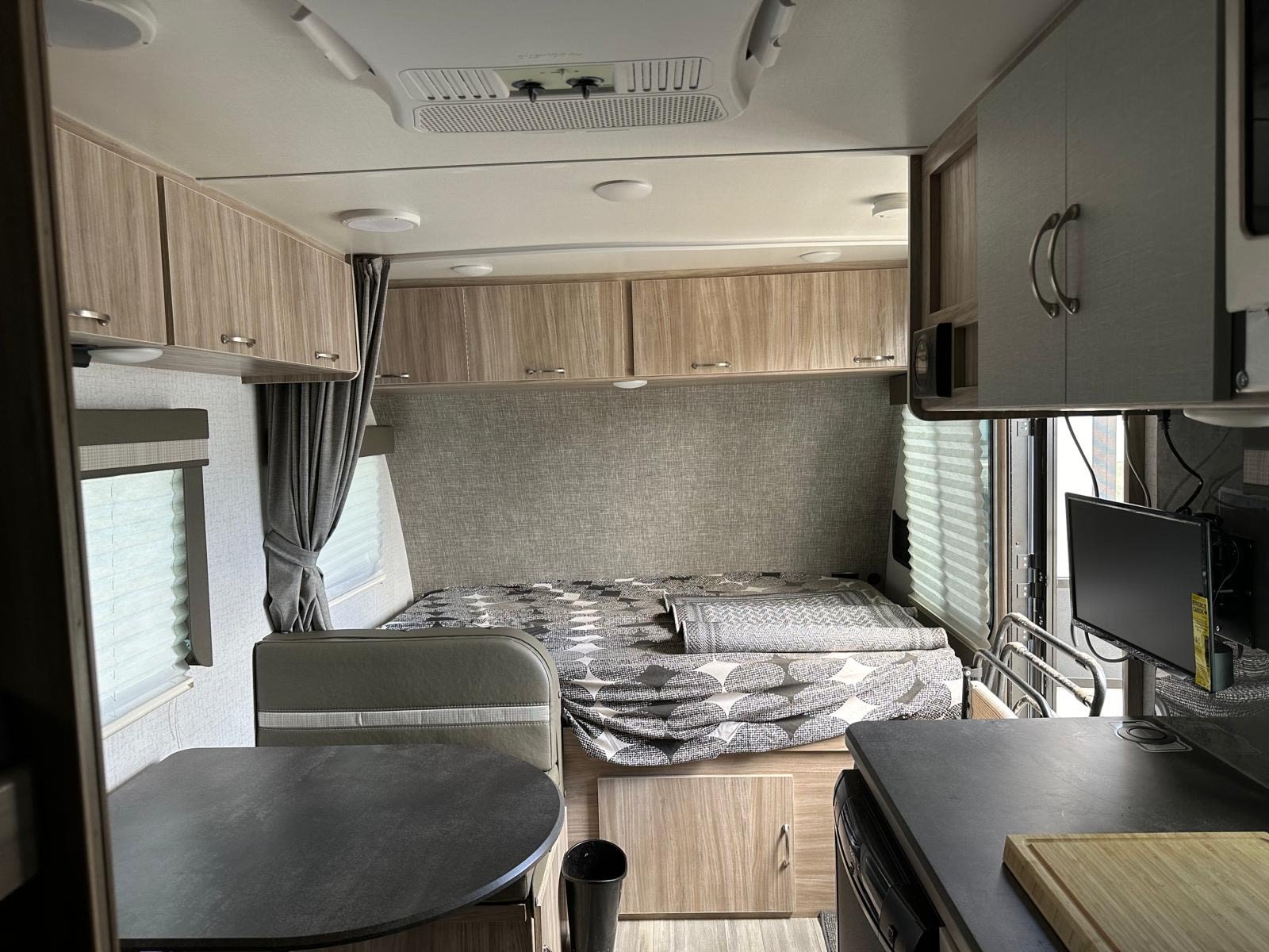Cozy RV rental interior with a bed, dinette, kitchen counter, and overhead cabinets for comfortable travel.. Winnebago Micro Minnie 2022