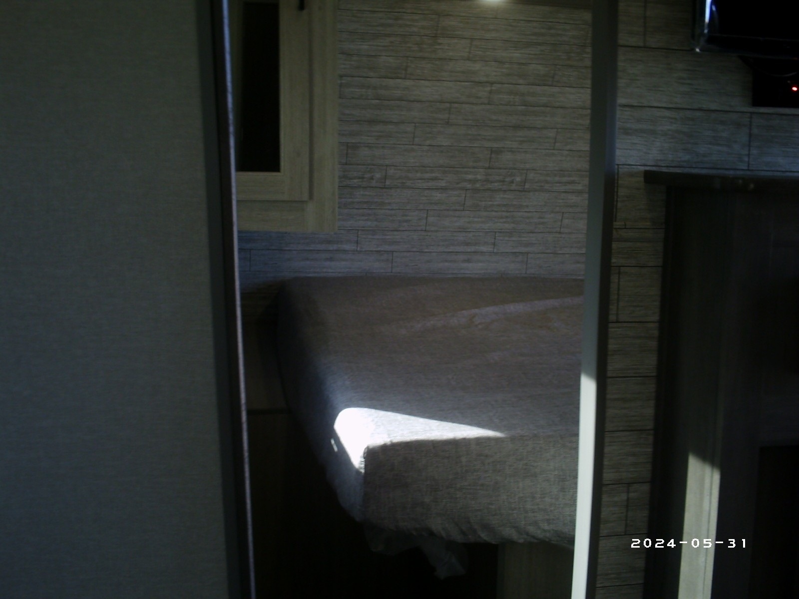 An RV rental bedroom seen through a doorway, with a bed bathed in sunlight and textured walls.. COACHMAN CATALINA 261BHS 2024