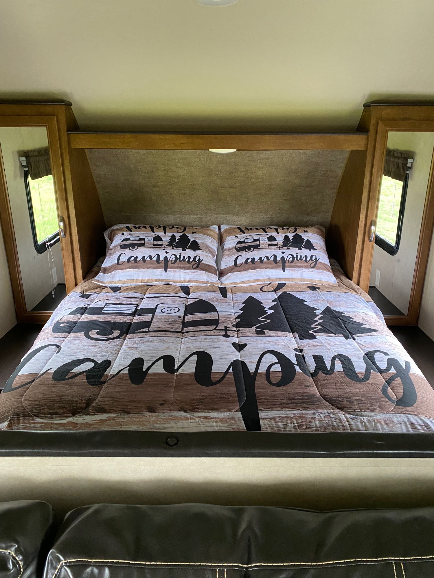 This RV rental bedroom features a "Happy Camping" bedding set with a travel trailer design.. Forest River Salem Cruise Lite 2017