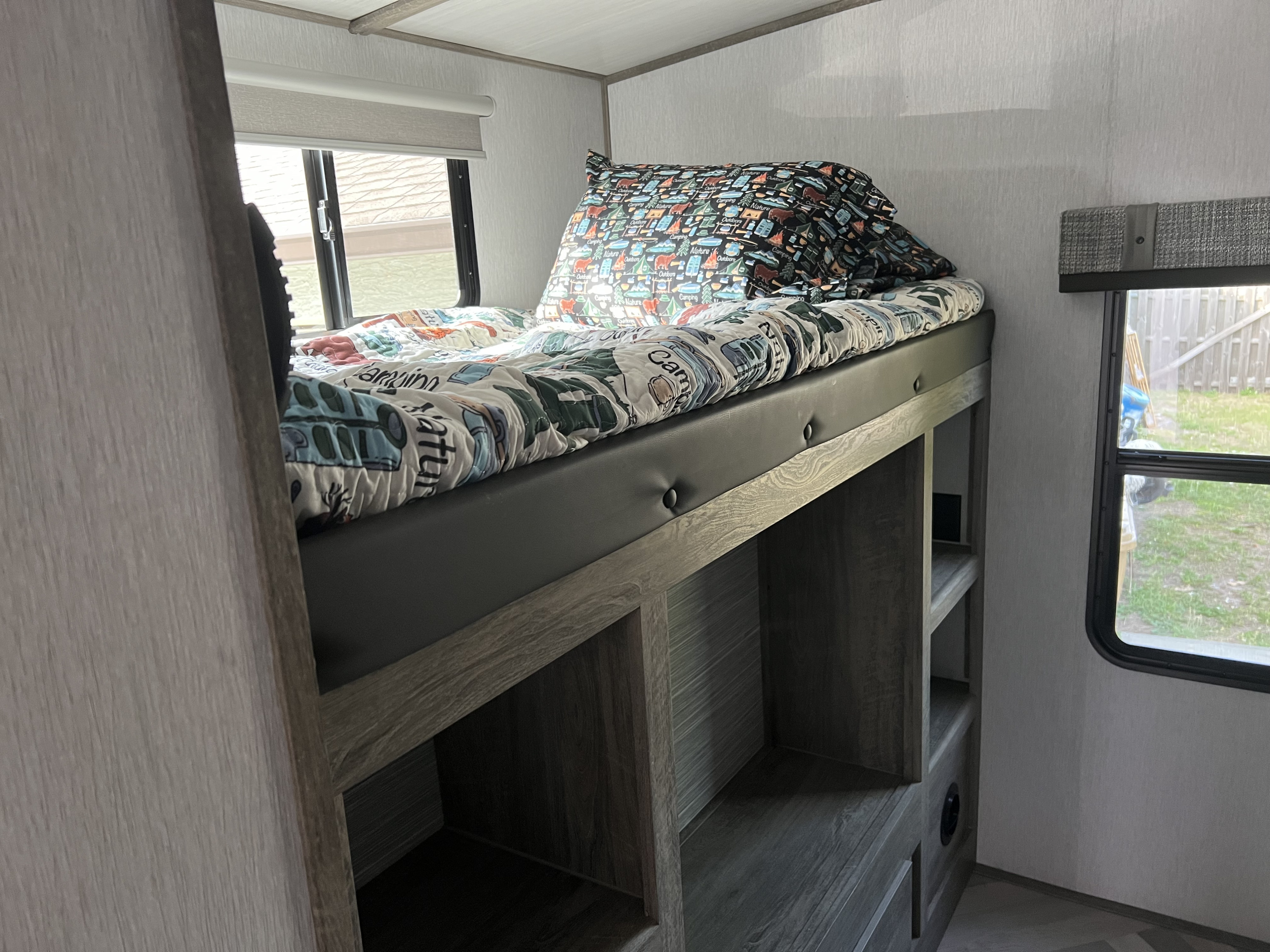 Inside an RV rental: a well-appointed bunk bed with vibrant camping bedding and convenient integrated storage shelves.. Forest River Salem Hemisphere 2022