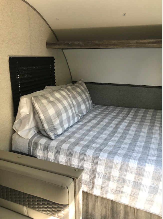 Cozy RV rental bedroom with a comfy bed, grey checkered bedding, and white pillows. A great spot for rest on the road.. Forest River Salem FSX 2021