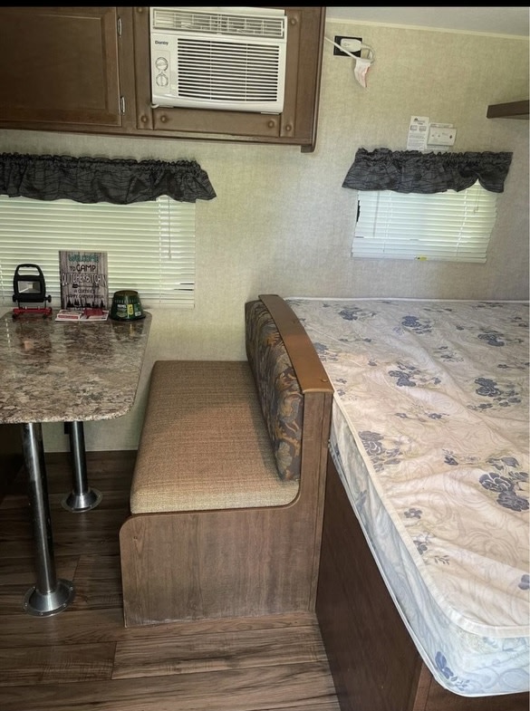 Cozy RV rental interior featuring a dinette, comfortable bed, and convenient AC unit, perfect for travel.. Keystone RV Hideout 2016