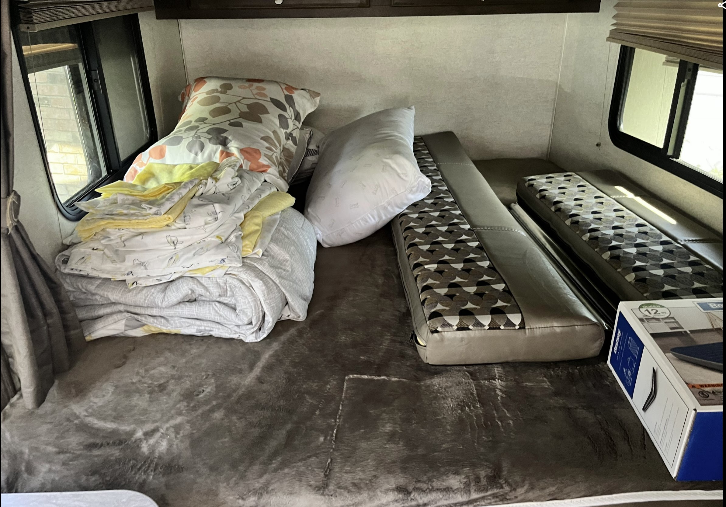 RV rental interior showing bunk beds with patterned cushions, pillows, and folded bedding, plus an air mattress box.. Starcraft Launch Outfitter 2018