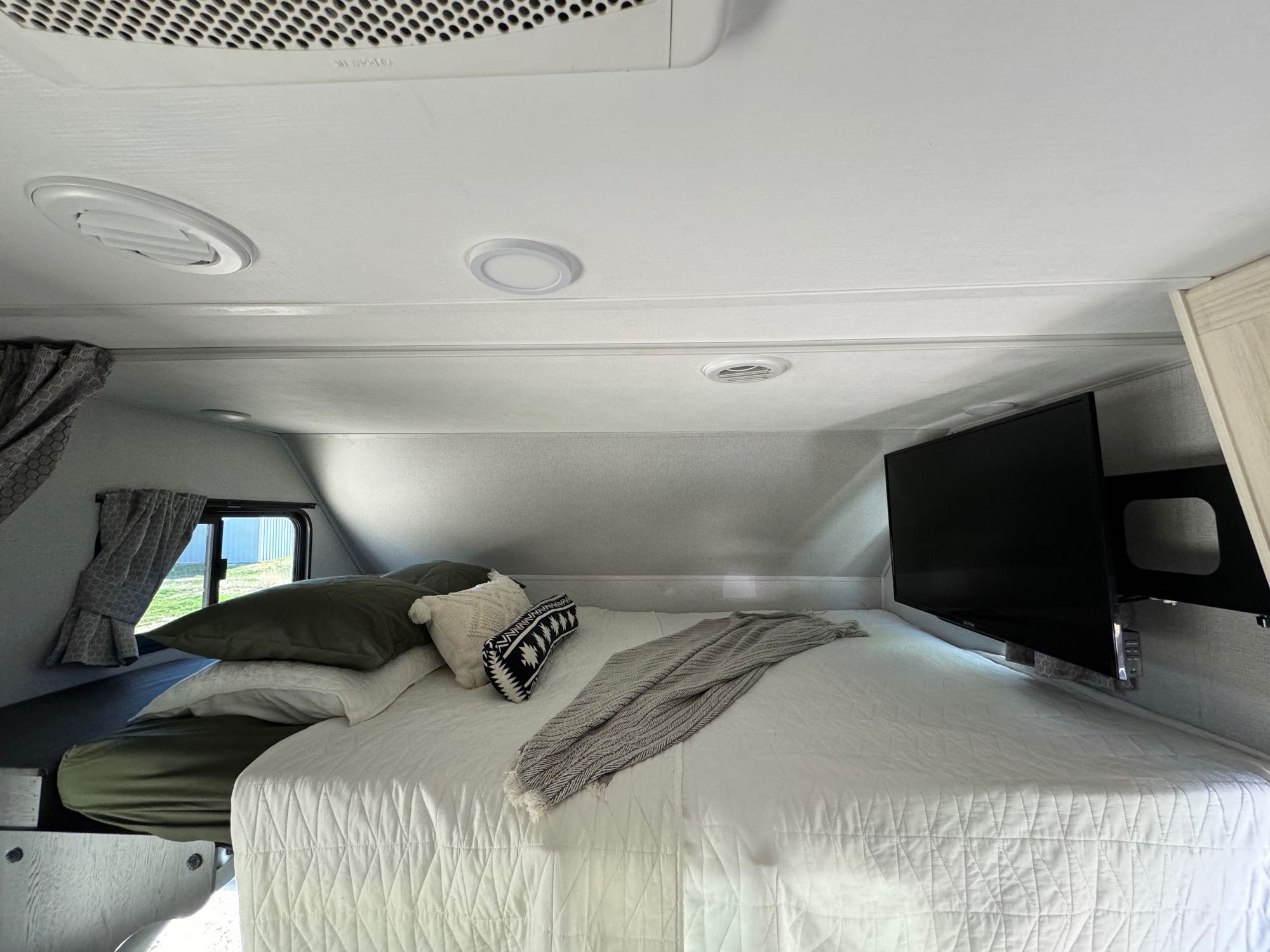 Comfortable RV rental bedroom with a large bed, TV, and window view. Perfect for your next trip!. Forest River Sunseeker LE 2021