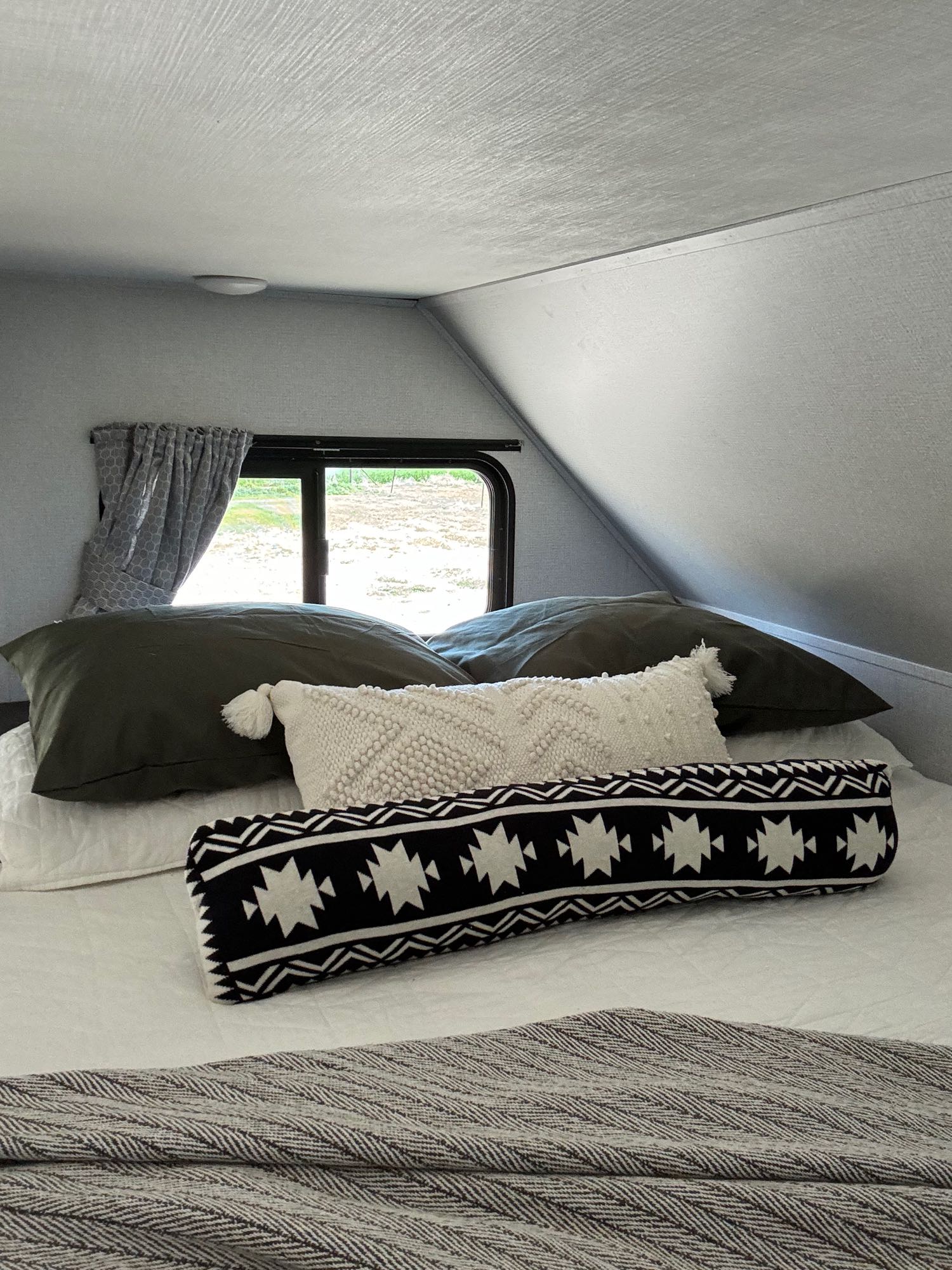 Cozy RV rental bedroom featuring a bed with textured pillows and an outdoor view.. Forest River Sunseeker LE 2021