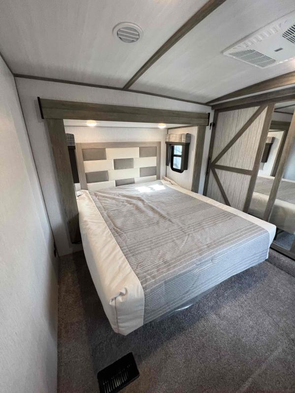 Spacious RV rental bedroom featuring a comfortable bed, stylish headboard, and mirrored closet doors.. Forest River Wildwood Heritage Glen 2020