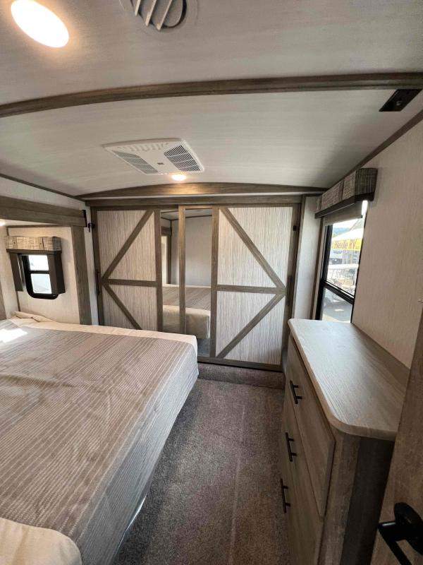 Step inside this comfortable RV rental bedroom, featuring a large bed, mirrored closet, and dresser for your travel needs.. Forest River Wildwood Heritage Glen 2020