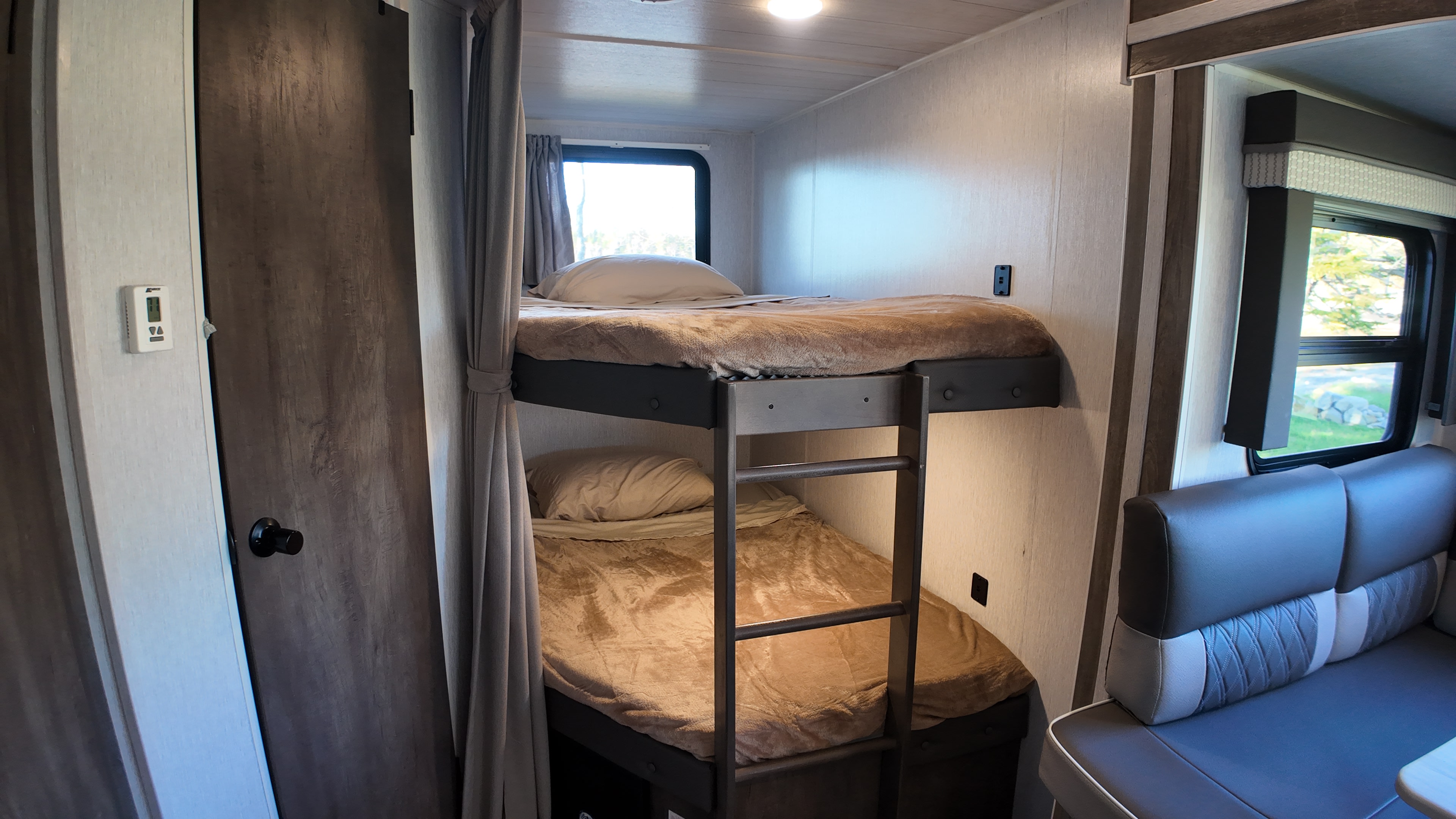 RV rental interior featuring cozy bunk beds with curtains and a comfortable dinette seating area.. Forest River Wildwood X-Lite 2022