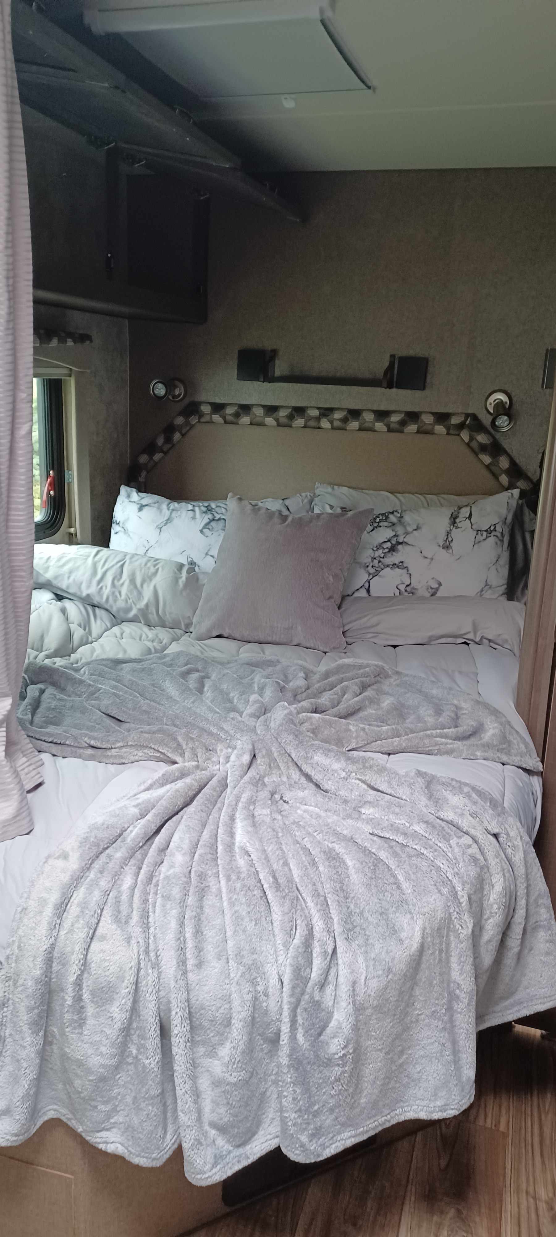 Cozy RV rental bedroom: a neatly made bed with a plush light grey blanket & marble-patterned pillows for your travels.. Adventurer Adventurer Motorhome 2018
