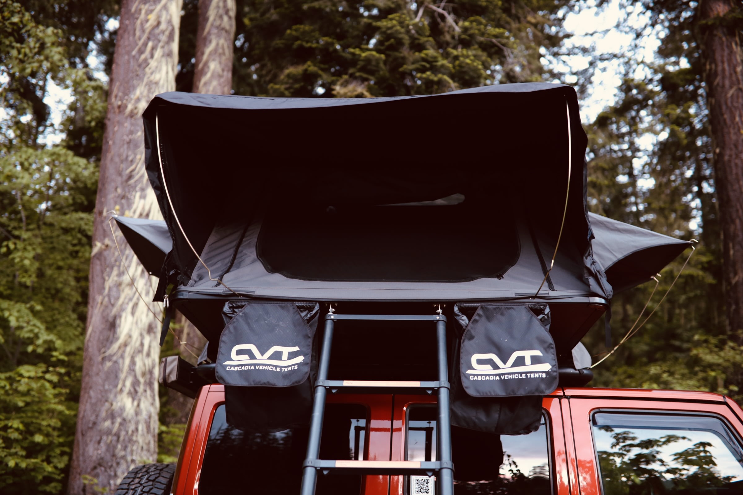 RV rental ready: A black Cascadia Vehicle Tents (CVT) roof-top tent is set up on a red vehicle, providing elevated camping.. Jeep Wrangler Unlimited 2014