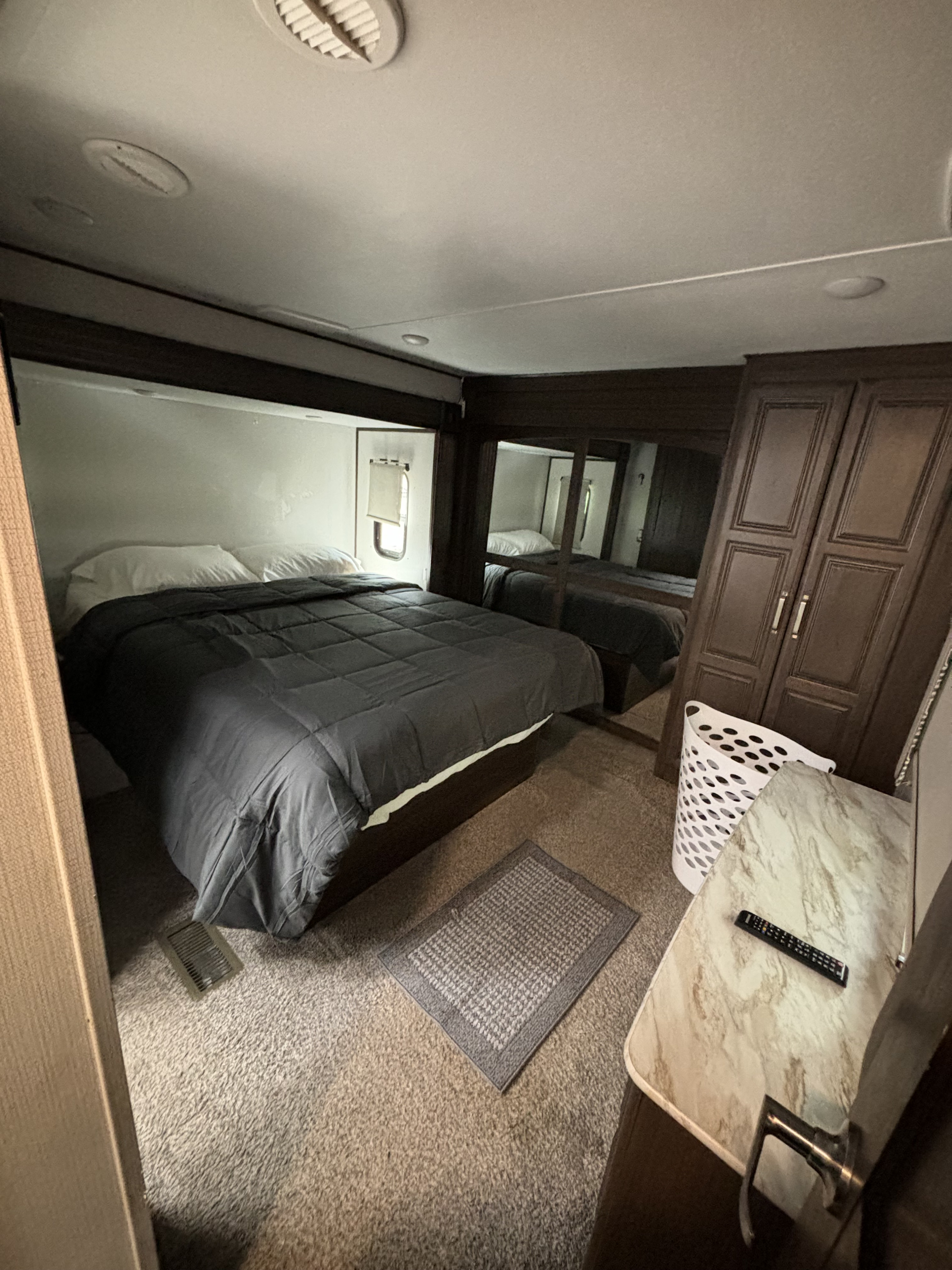 Comfortable RV rental bedroom: dark bed, white pillows, window, mirrored wardrobe, and carpeted floor.. Keystone RV Avalanche 2021