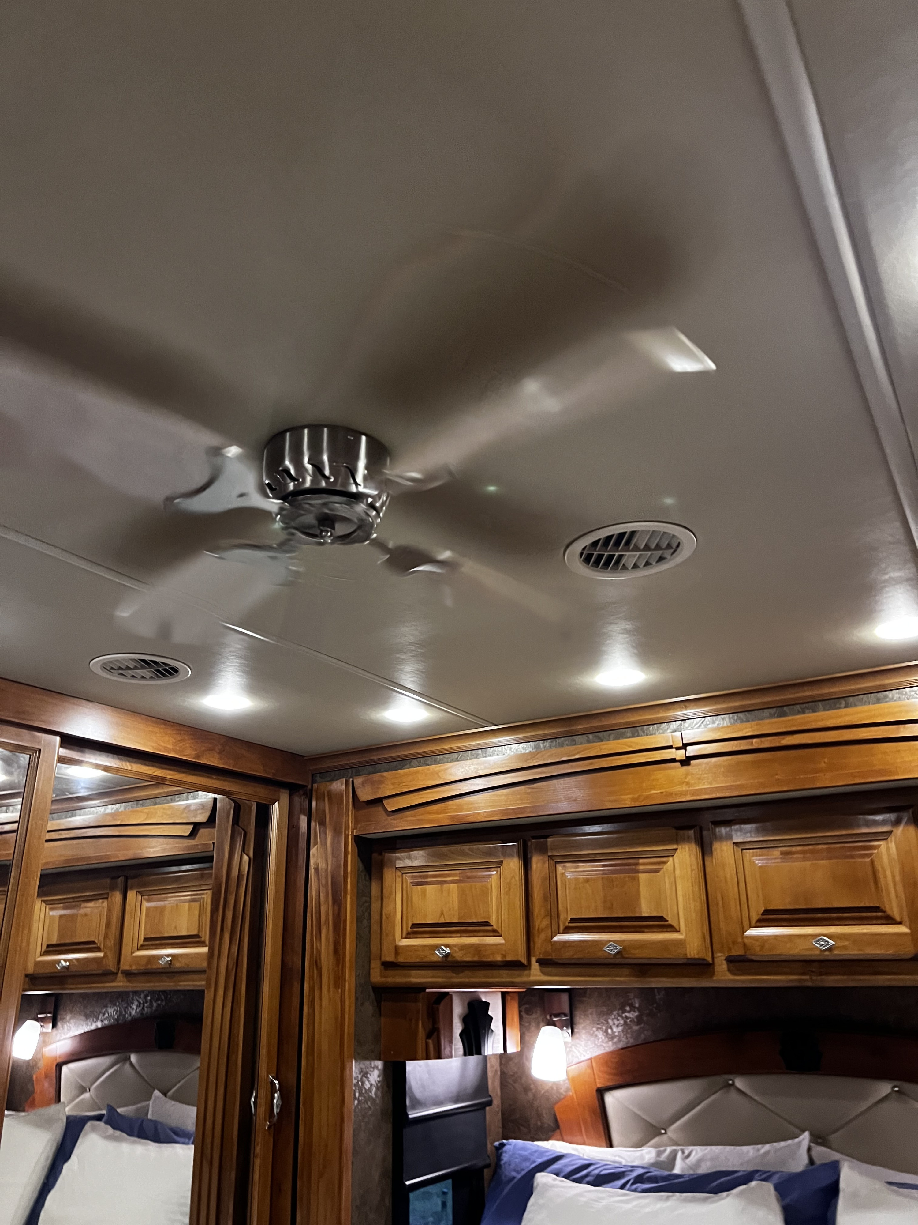 Inside an RV rental: bedroom amenities include a spinning ceiling fan, wood cabinets, and bright overhead lighting.. Allegro Allegro Motorhome 2015