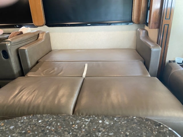 Tan pull-out sofa bed, extended for sleeping in an RV rental. Cozy comfort for your travels.. Fleetwood Southwind 37H 2018