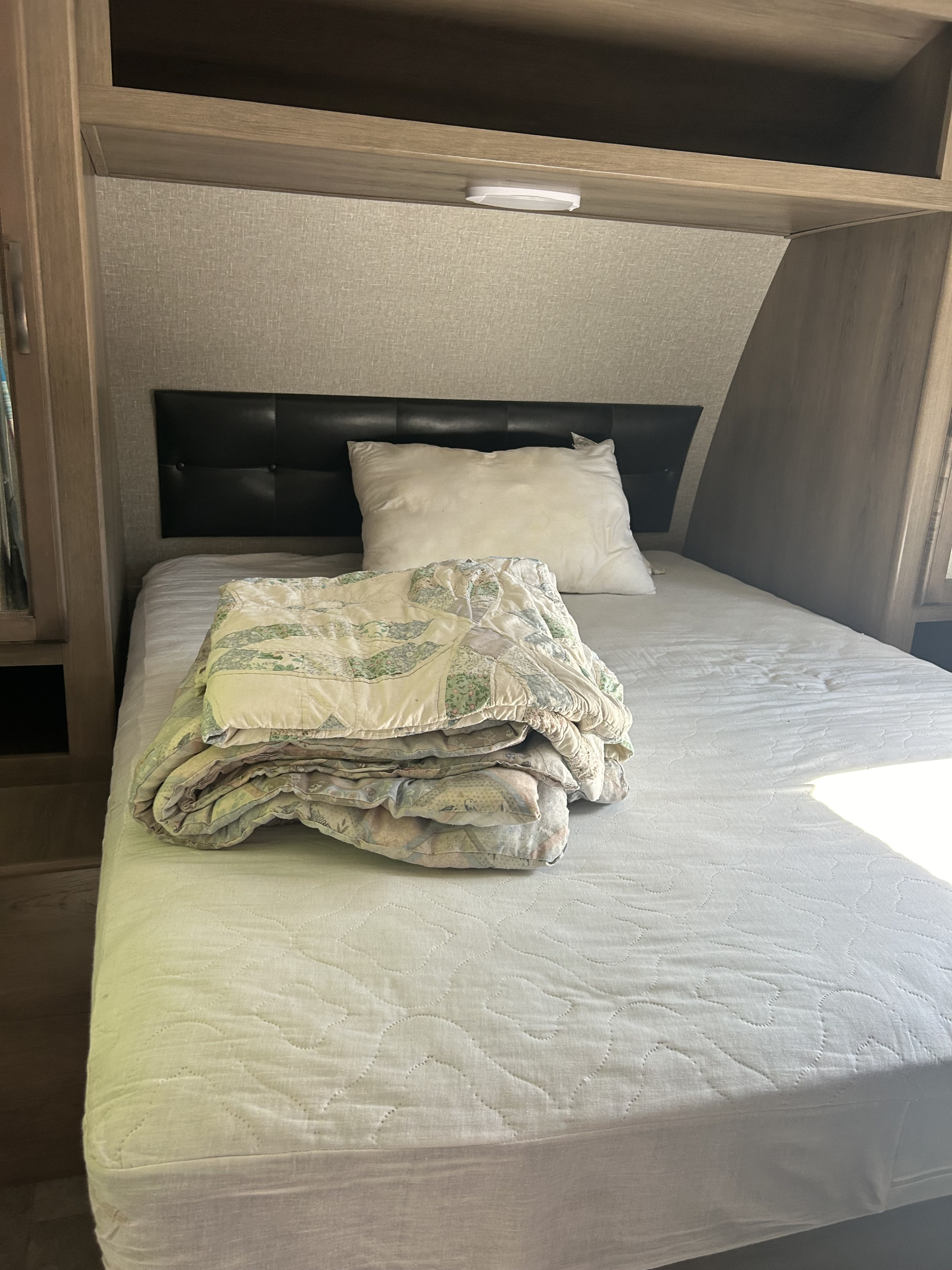 RV rental bedroom features a comfy bed with a pillow & folded quilt, plus an overhead cabinet with a light.. Travel Lite Other 2020