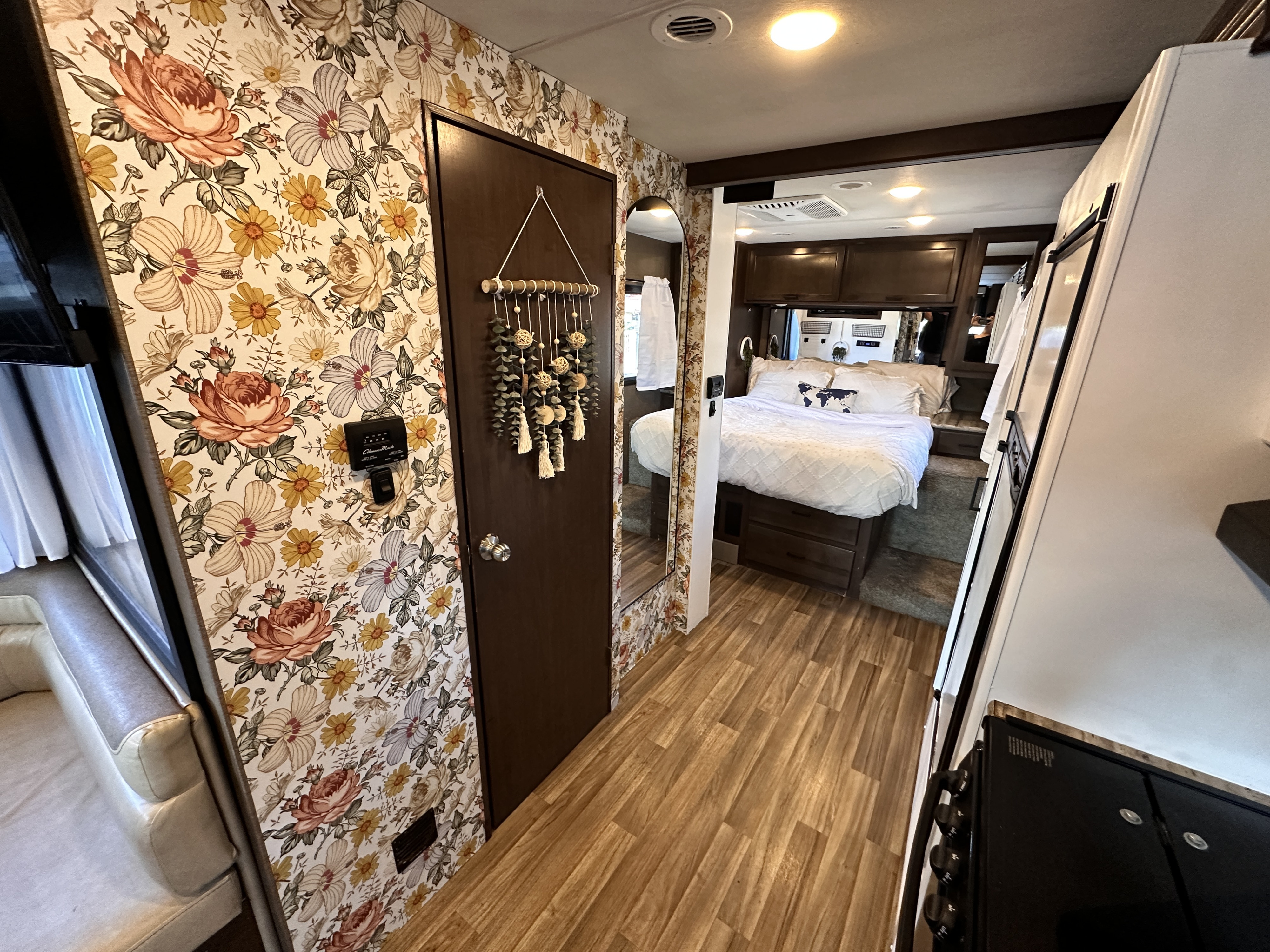 This inviting RV rental showcases vibrant floral wallpaper, a cozy bedroom, and warm wood flooring, offering stylish travel.. Thor Motor Coach A.C.E 2018