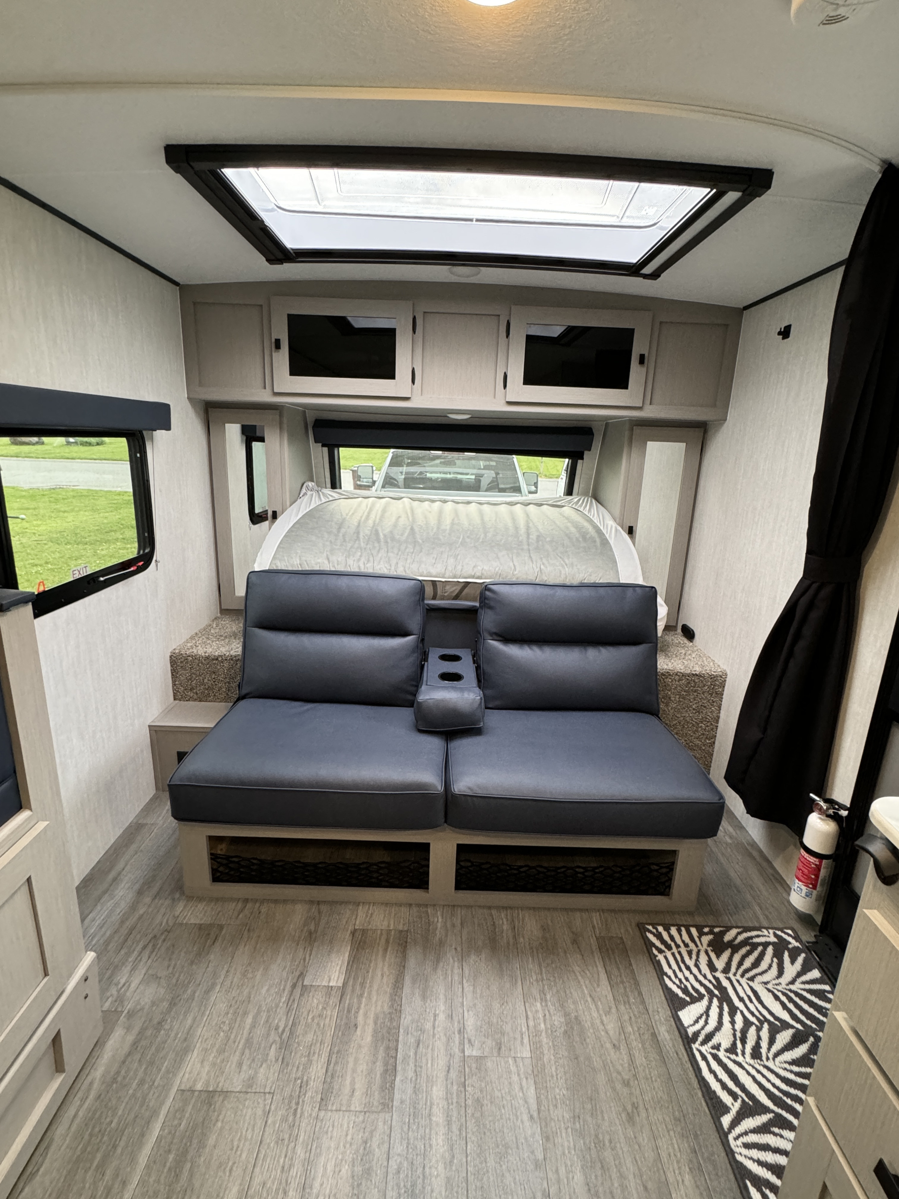 Modern rv rental interior: grey seating with cupholders, a bed, skylight, and wood-look flooring.. Forest River Coachmen Apex Nano 208BHS 2024