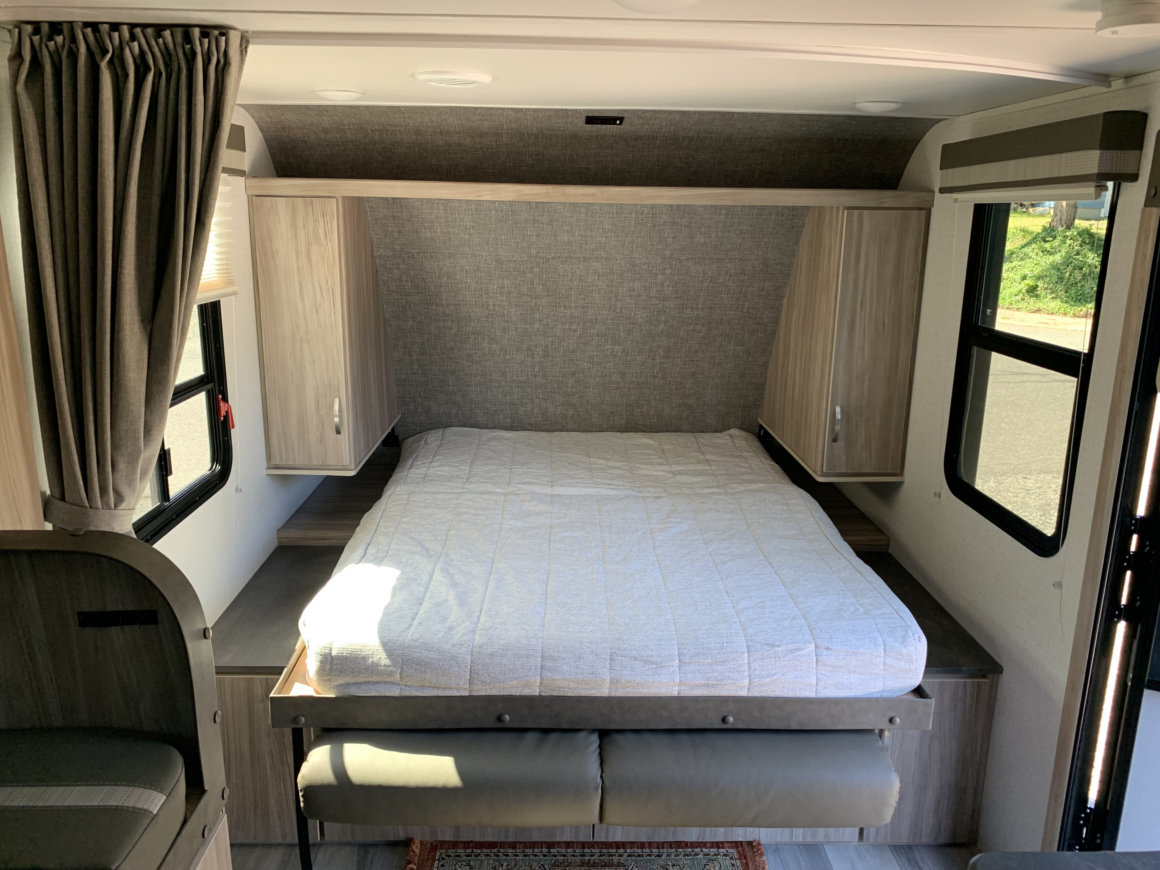 View of a modern RV rental bedroom: a comfortable bed with storage, bright windows, and stylish curtains.. Winnebago Micro Minnie 2306BHS 2022