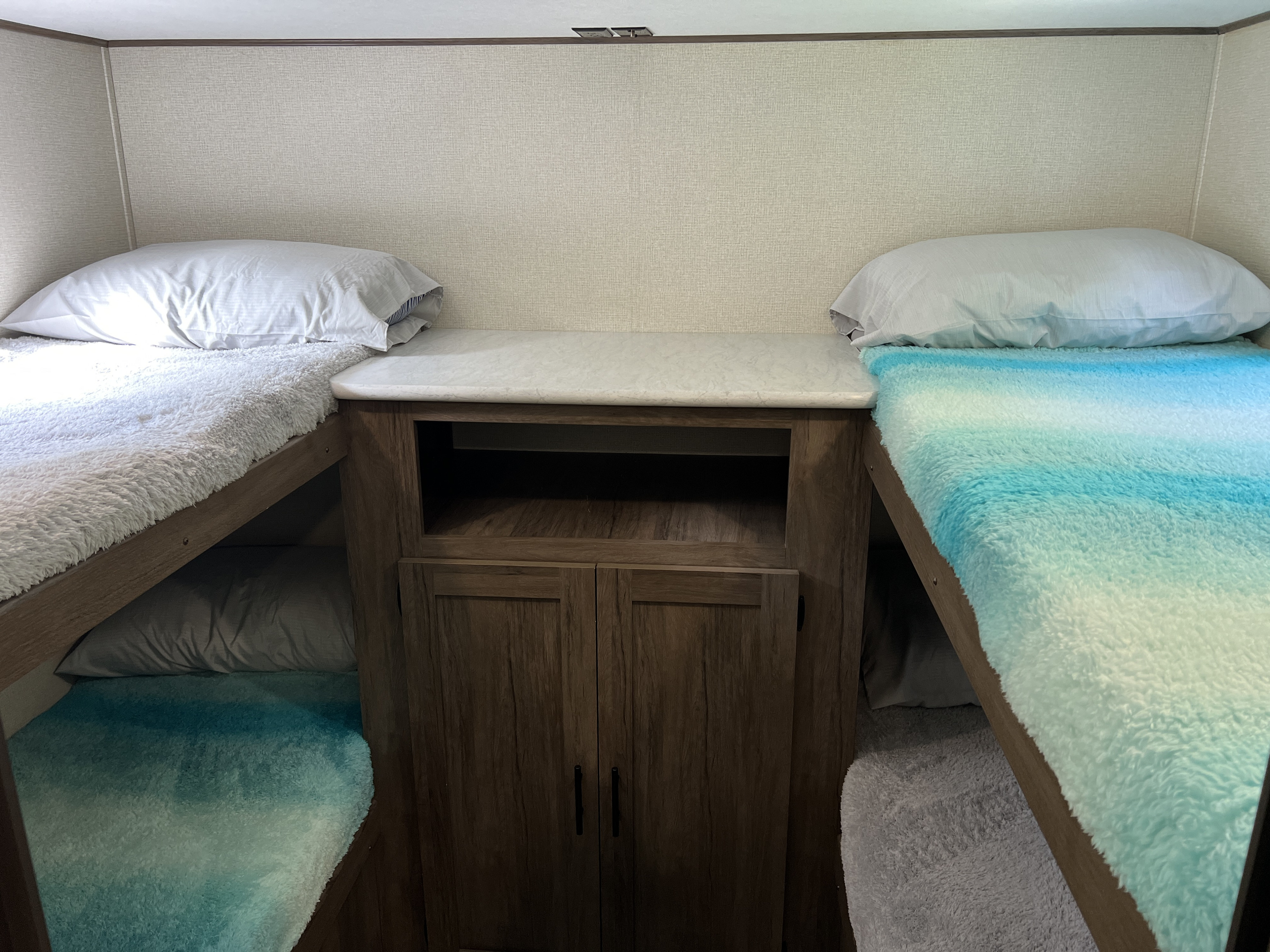 Inside an RV rental: cozy bunk beds with soft blankets and a central storage unit.. Avenger LE 2020