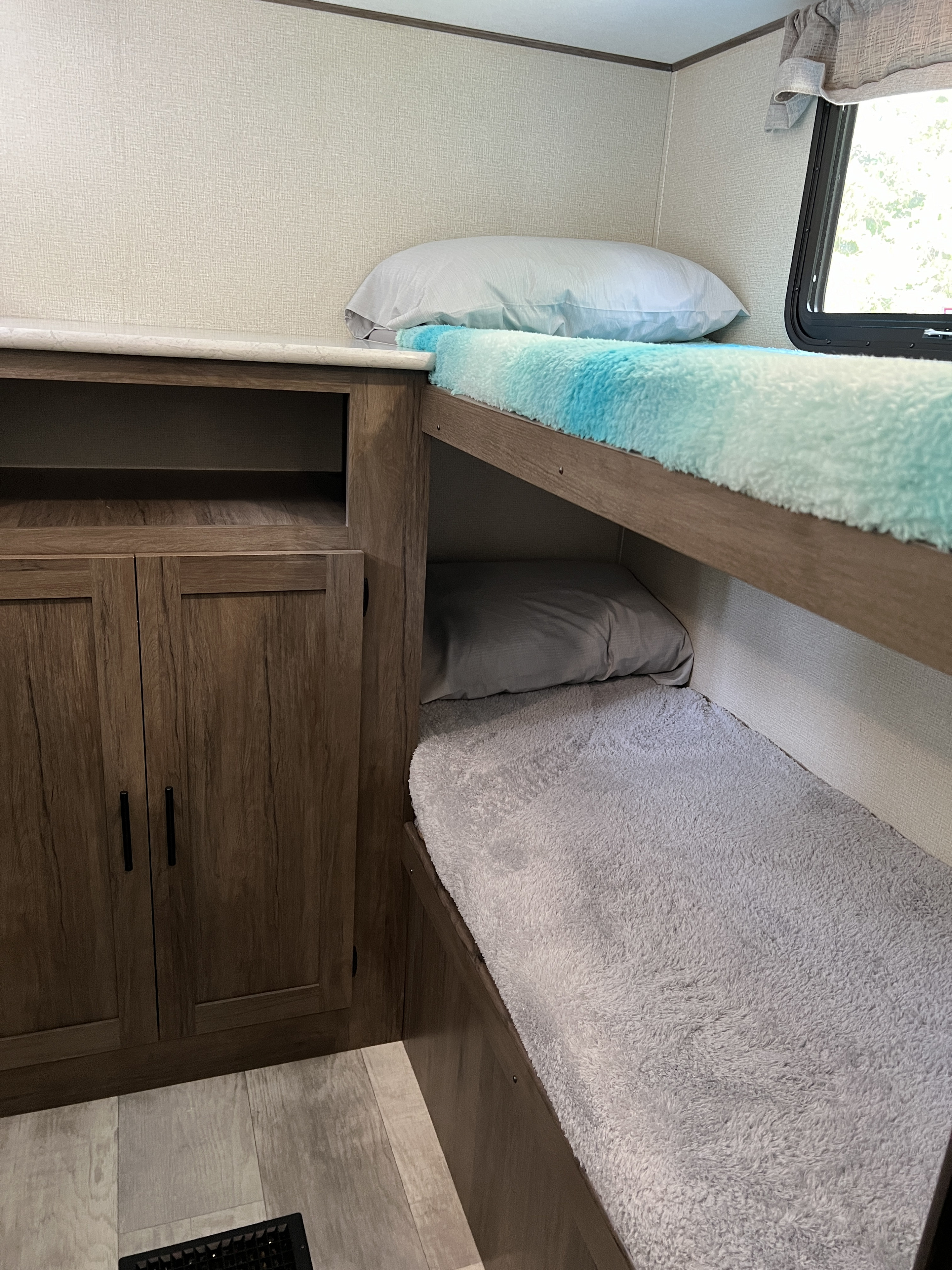 Cozy RV rental interior featuring two bunk beds with soft bedding and wood cabinetry for storage. Ideal for family adventures.. Avenger LE 2020