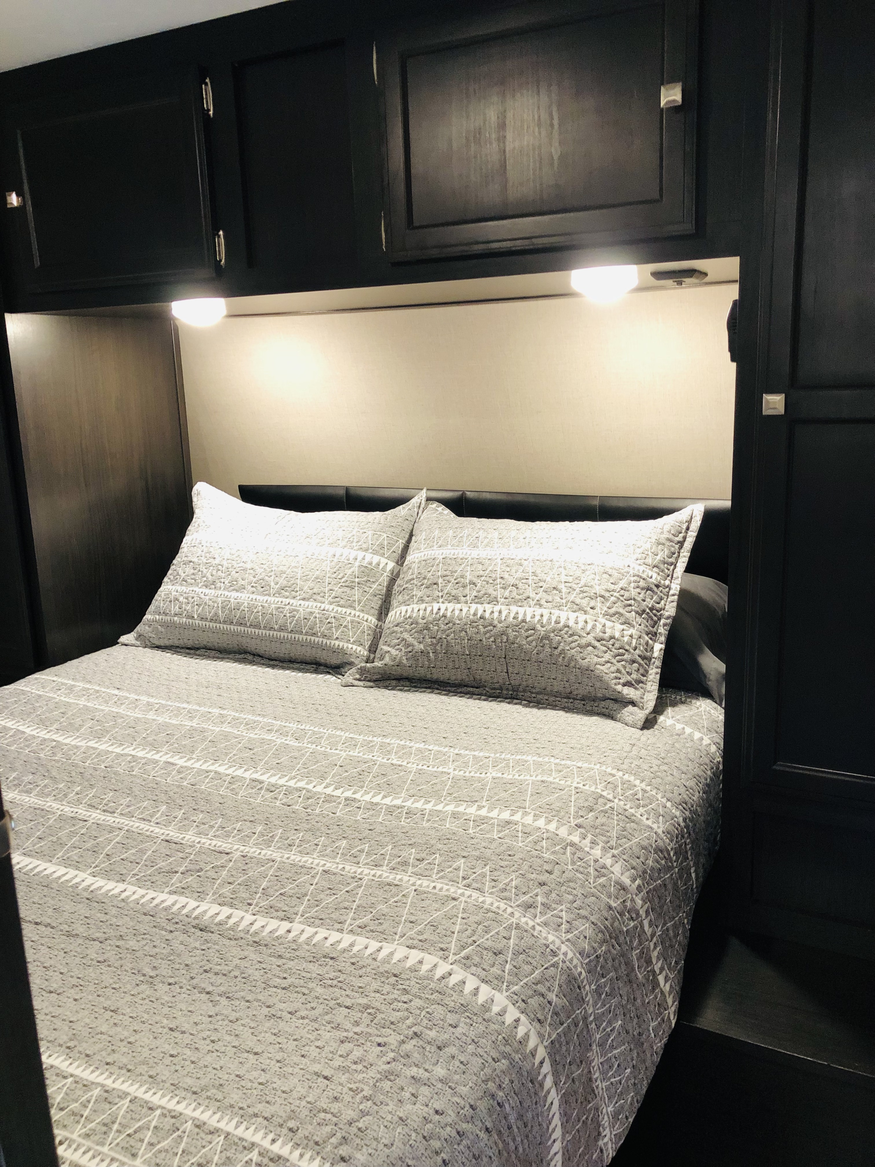 RV rental bedroom: Dark cabinets, warm lights, and gray patterned bedding create a cozy sleeping space.. Sport Trek Sport Trek Trailer 2019