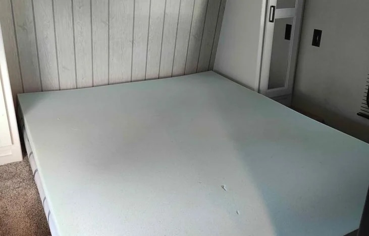 RV rental bedroom showing a light blue foam mattress, a compact sleeping area with paneled walls.. Keystone RV Hideout 2022