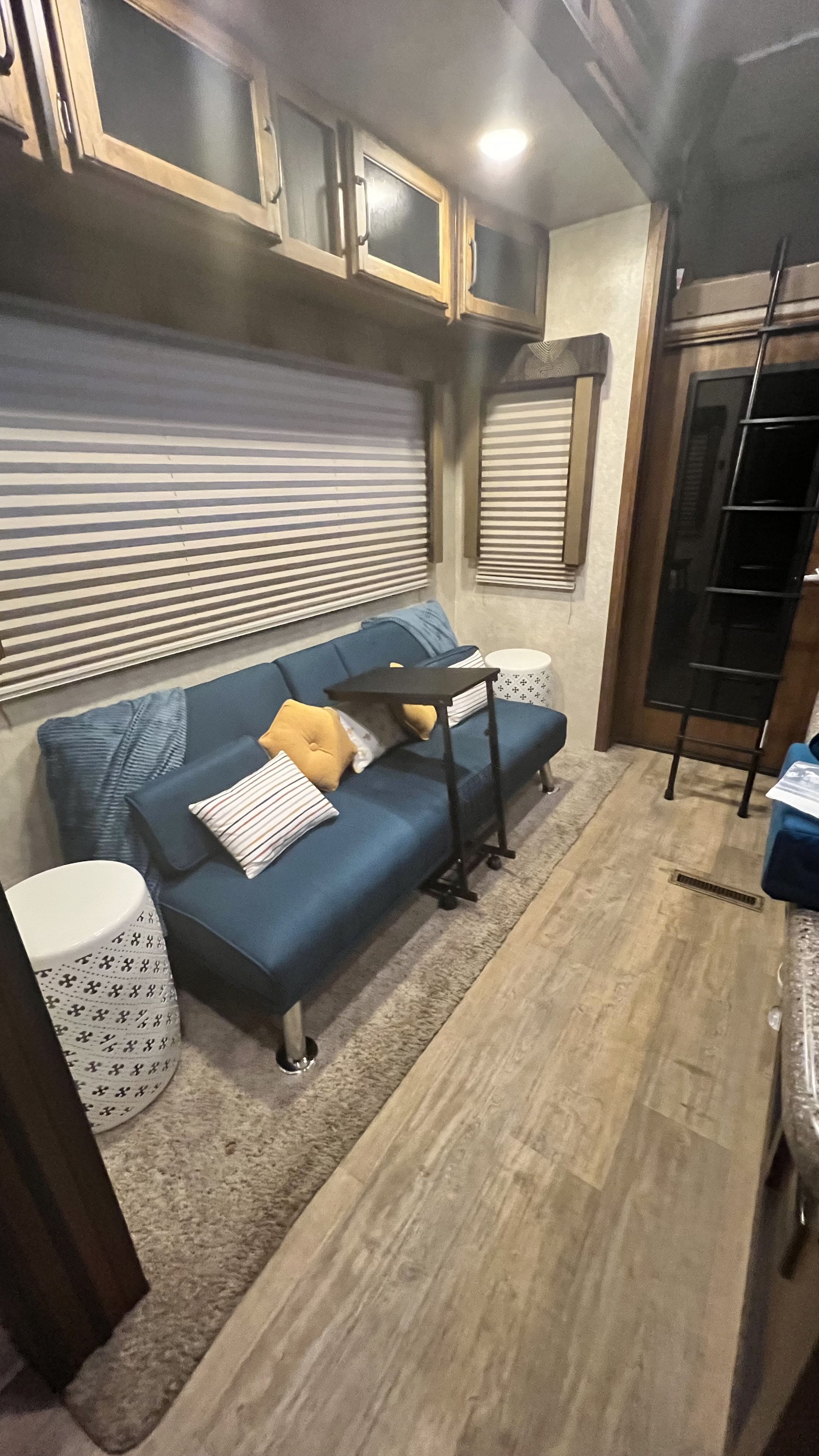 Cozy RV rental interior: blue sofa with pillows, adjustable table, and stylish decor. Perfect for travel comfort.. Keystone Carbon 2016