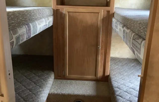 RV rental features: compact sleeping area with two sets of bunk beds and a central storage cabinet.. Jayco Jayfeather 2007