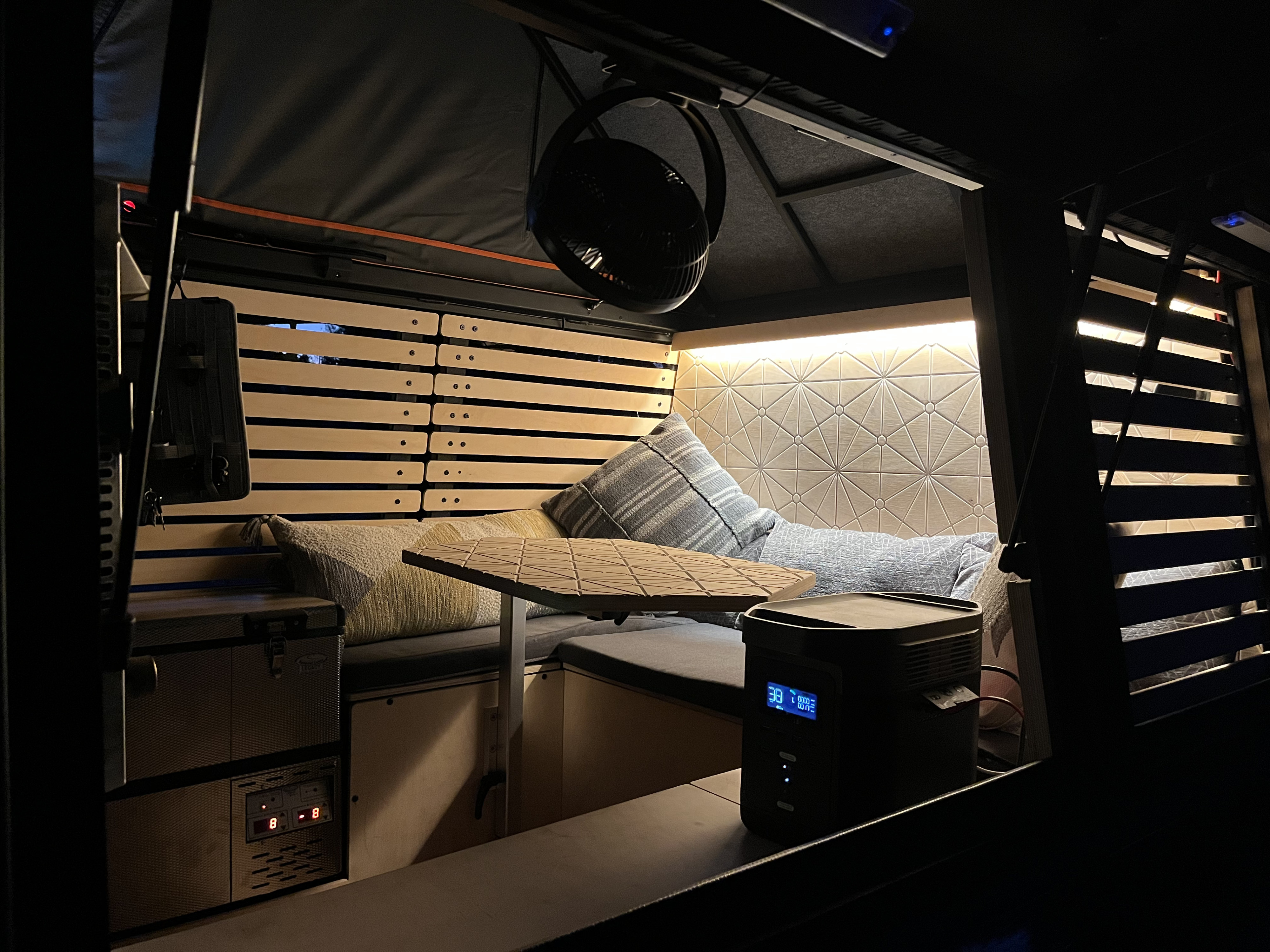 Cozy RV rental interior at night. Features comfy seating, adjustable table, and power station. Ideal for van life adventures.. Airstream Overlander 2019