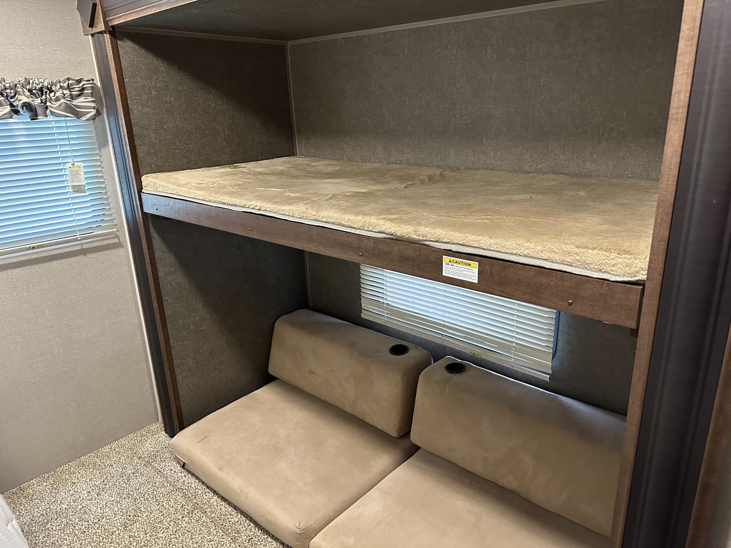 RV rental interior: cozy bunk beds with soft bedding and a lower seating area with cupholders and a window.. Keystone Hideout 2017