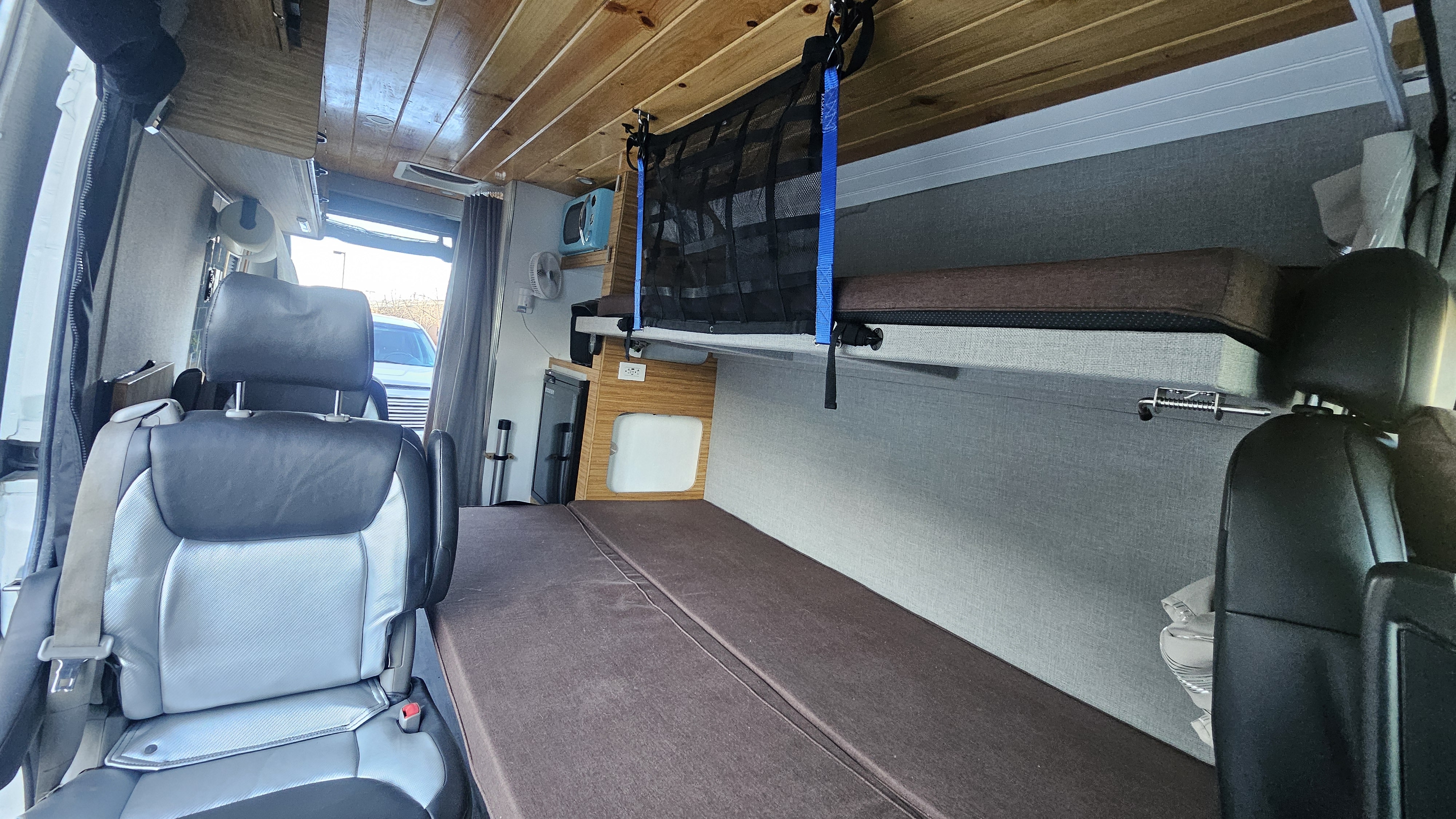 RV rental interior: A custom camper van featuring convertible seating/bed, upper bunk with safety net, and compact kitchen area.. Ram Promaster 2015