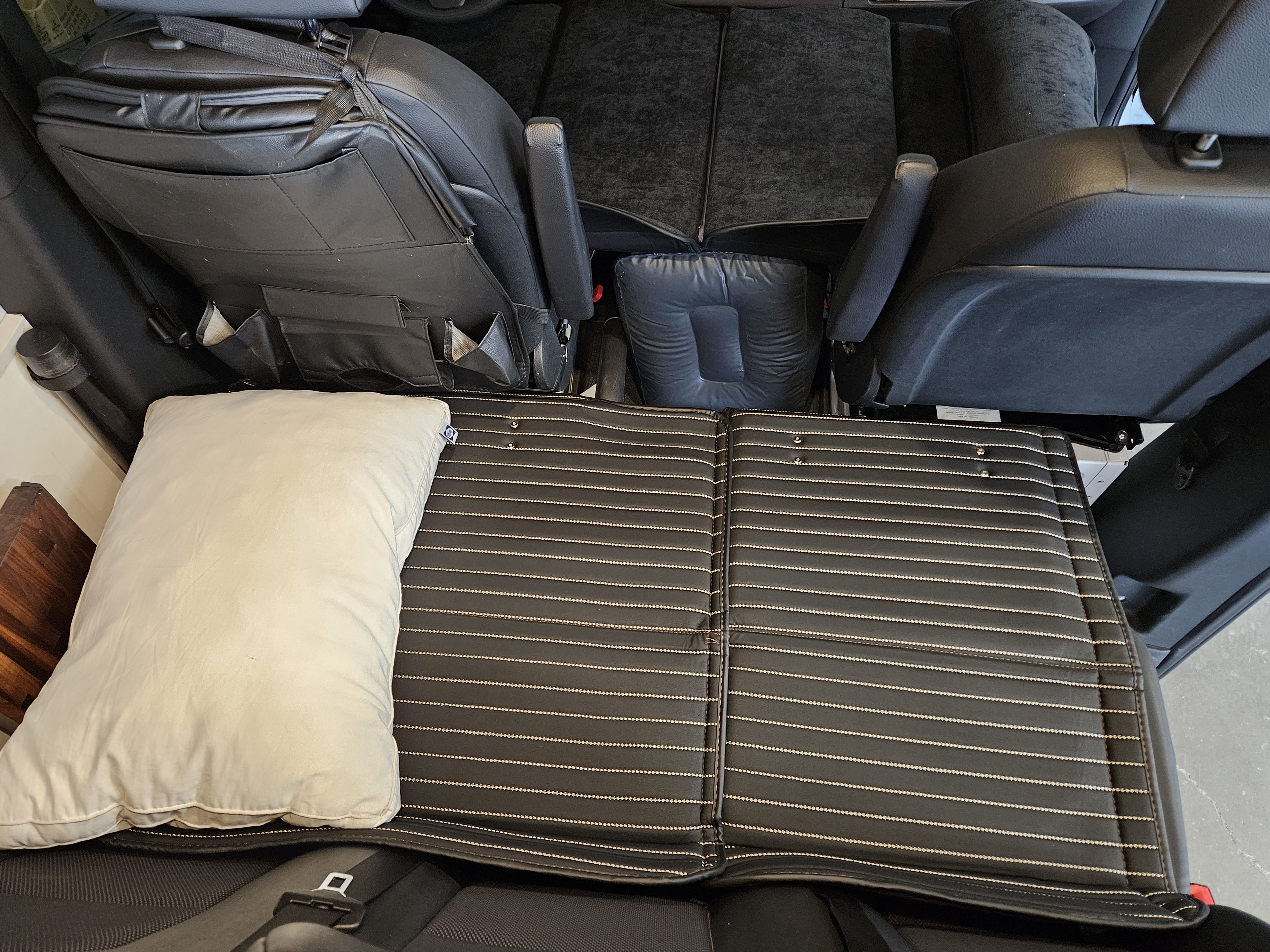 Custom sleeping setup in an RV rental, featuring a striped mattress pad and pillow for comfortable travel.. Mercedes-Benz Sprinter 2021