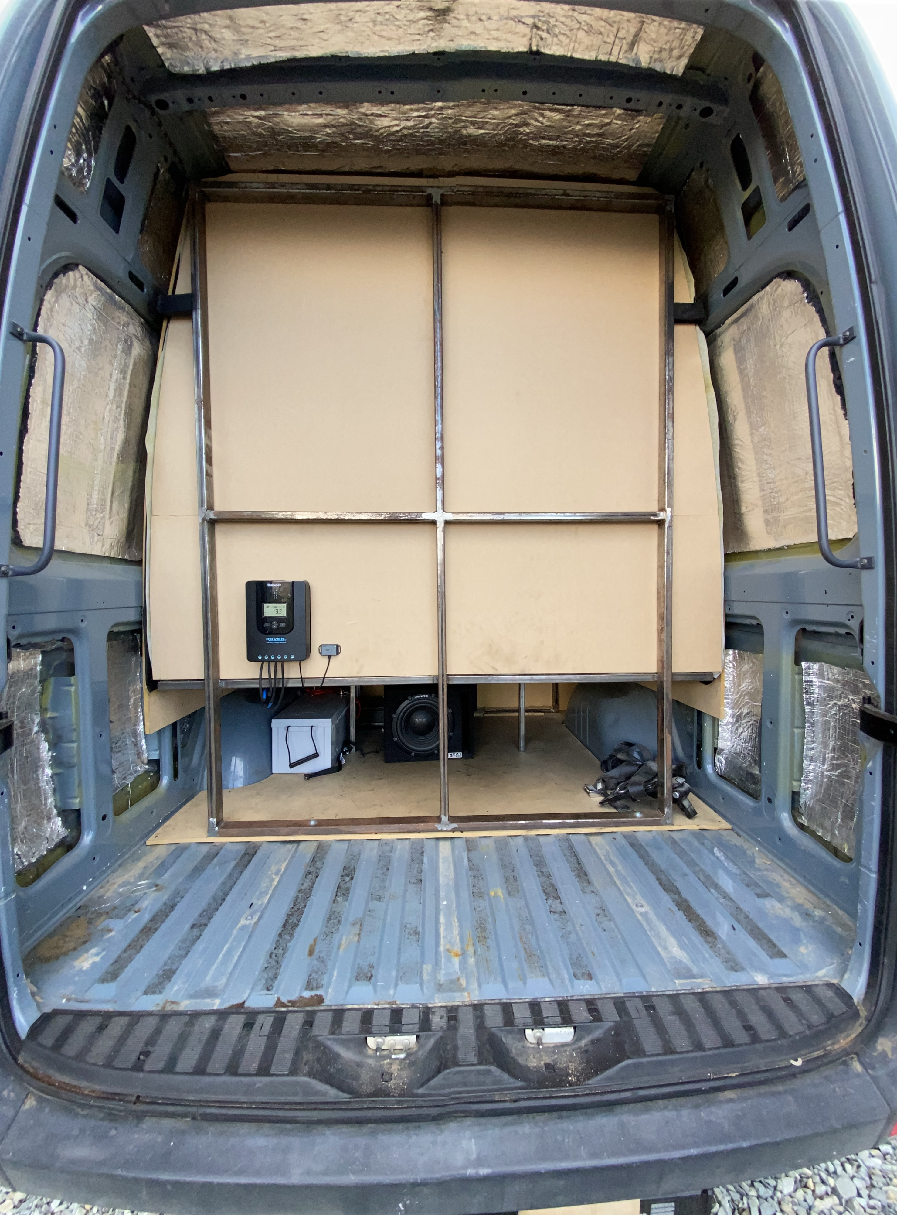 DIY RV rental build: Van interior with insulation, metal bed frame, solar charge controller, battery, and subwoofer.. Mercedes-Benz Sprinter 2014