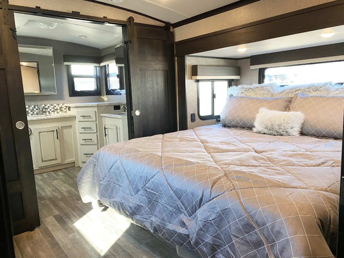 Cozy RV rental bedroom with connected bath, featuring a large bed, modern finishes & wood flooring.. Jayco North Point 2021