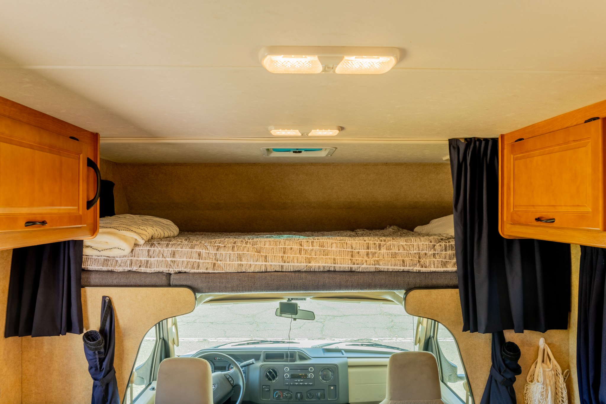 Cozy RV rental interior featuring an overhead bunk bed, front cab, and wooden storage cabinets, ready for adventure.. Thor Majestic 2015