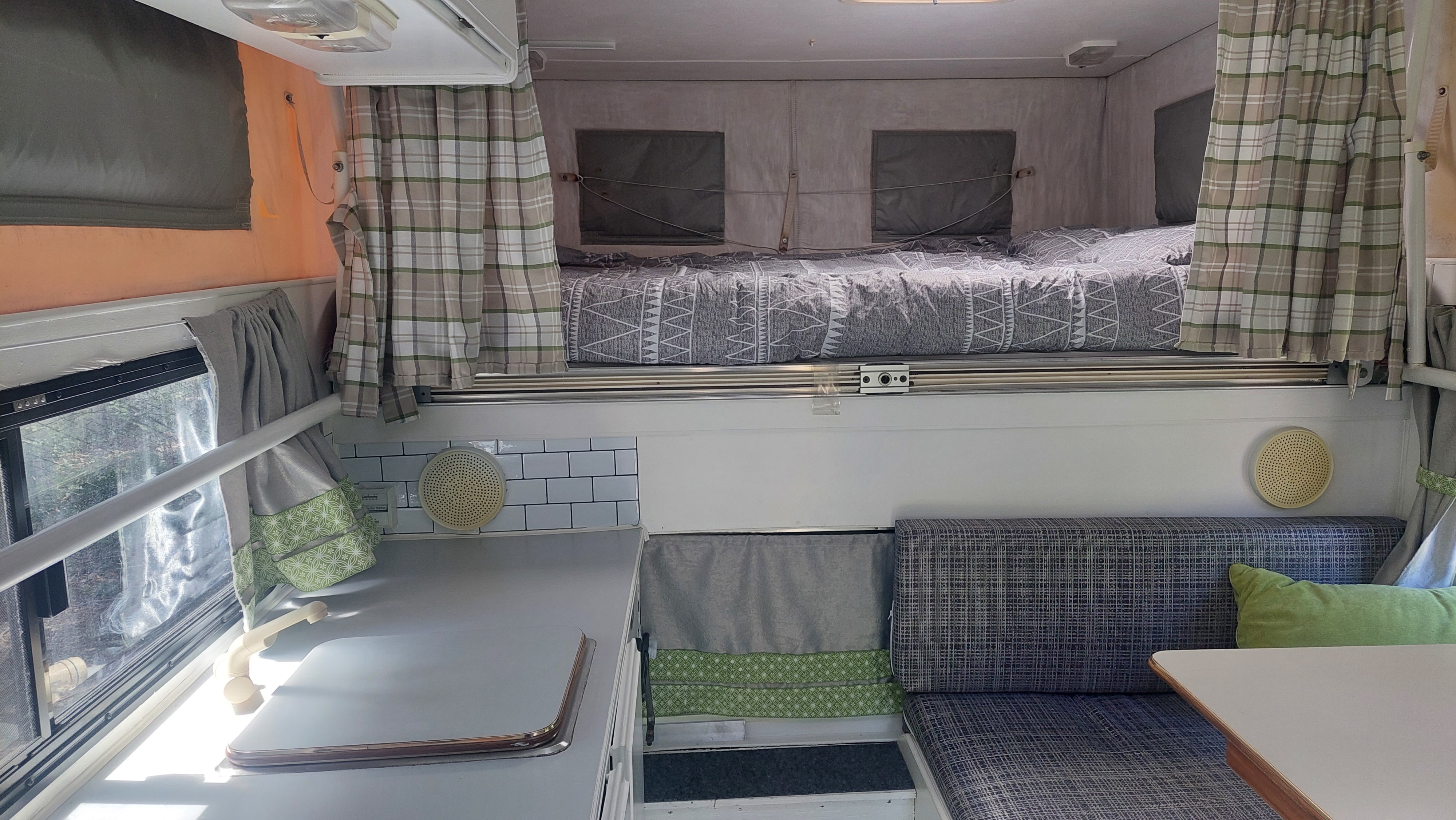 Step into this cozy RV rental, featuring an upper bed, compact kitchen, and inviting dinette area.. Ford F350 2015