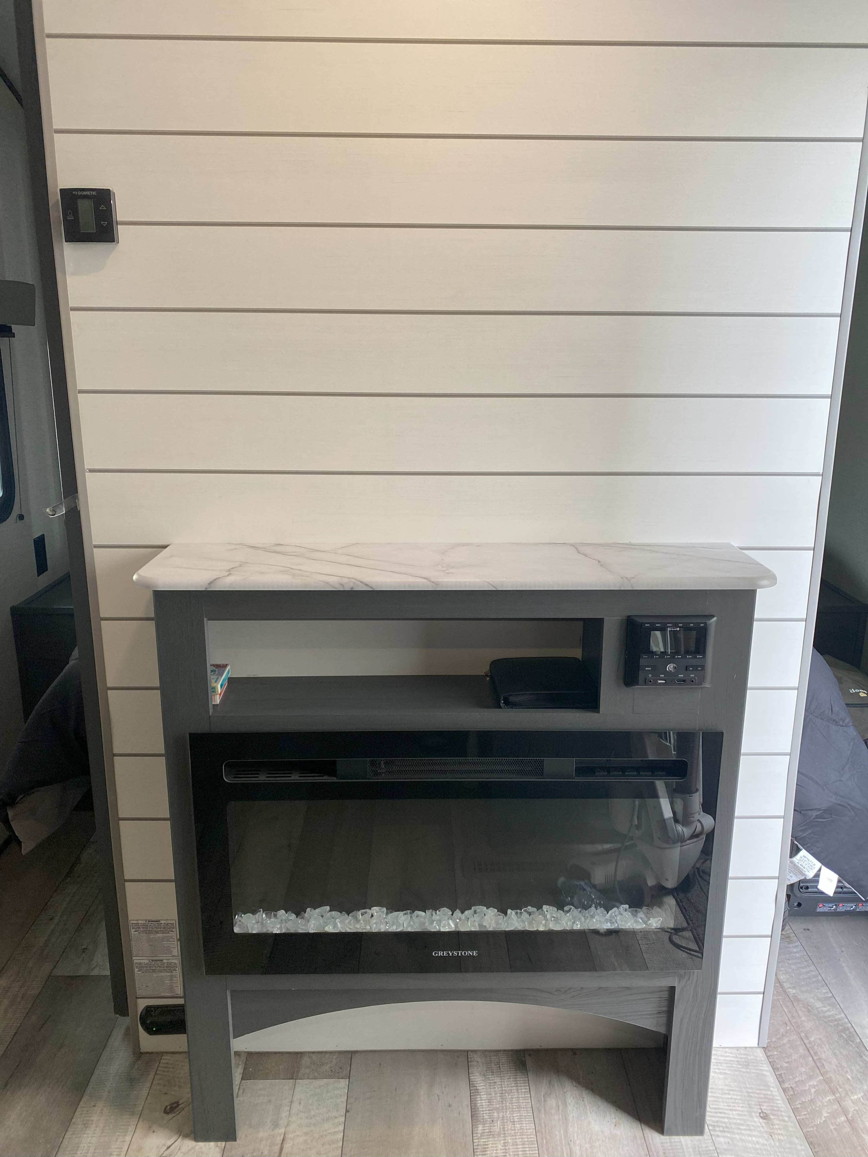 Modern RV rental interior featuring a cozy Greystone electric fireplace with shiplap wall & entertainment setup.. Aspen Trail Aspen Trail Trailer 2021