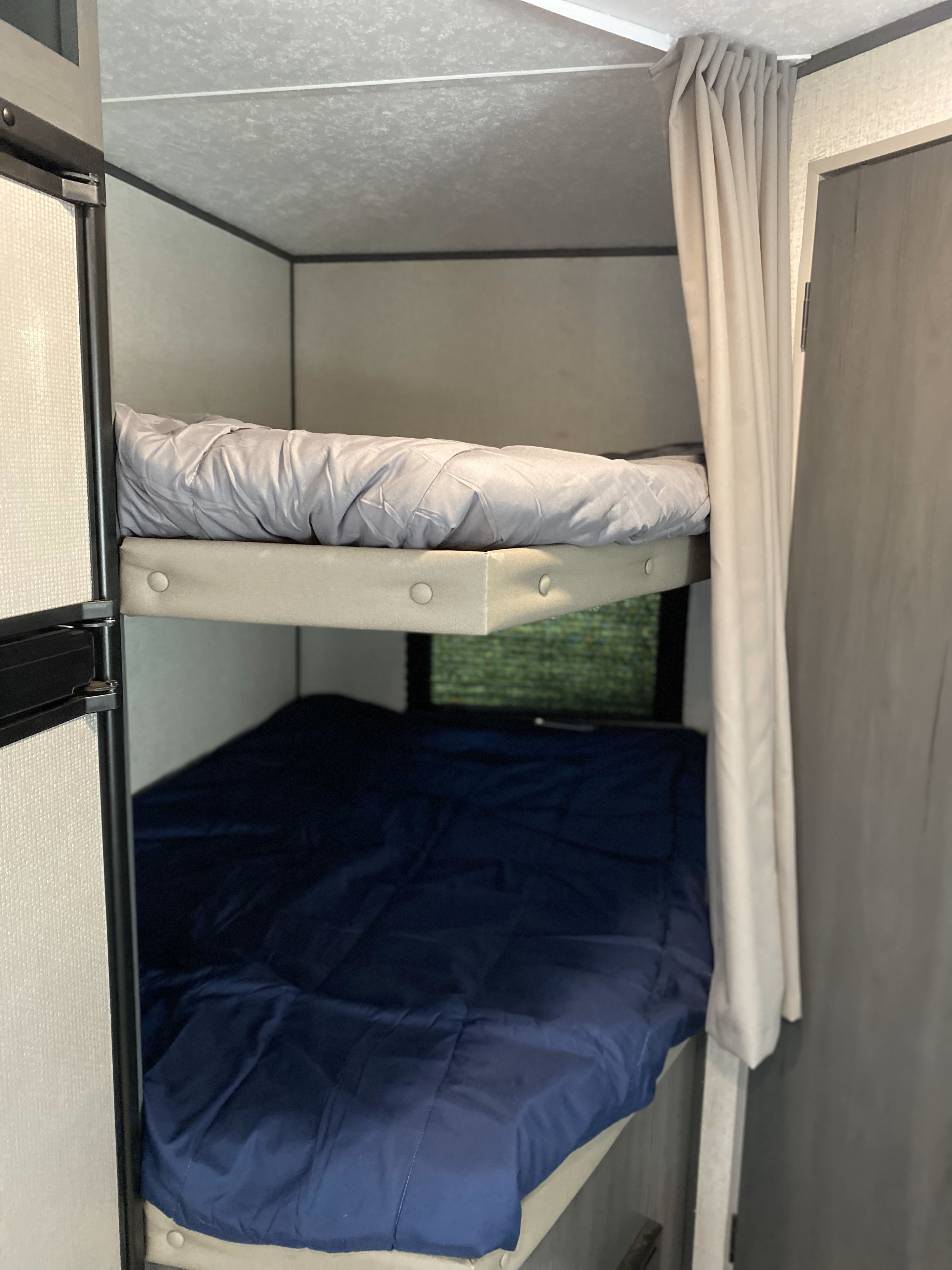RV rental bunk beds: A cozy sleeping area with a grey top bunk and navy lower bunk, plus a privacy curtain.. Aspen Trail Aspen Trail Trailer 2021