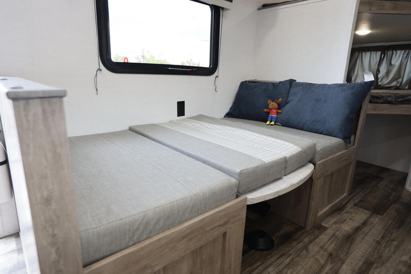 RV rental shows flexible interior: dinette seating converts to a bed, with blue pillows and a rear bunk area.. Grand river 22MB 2024