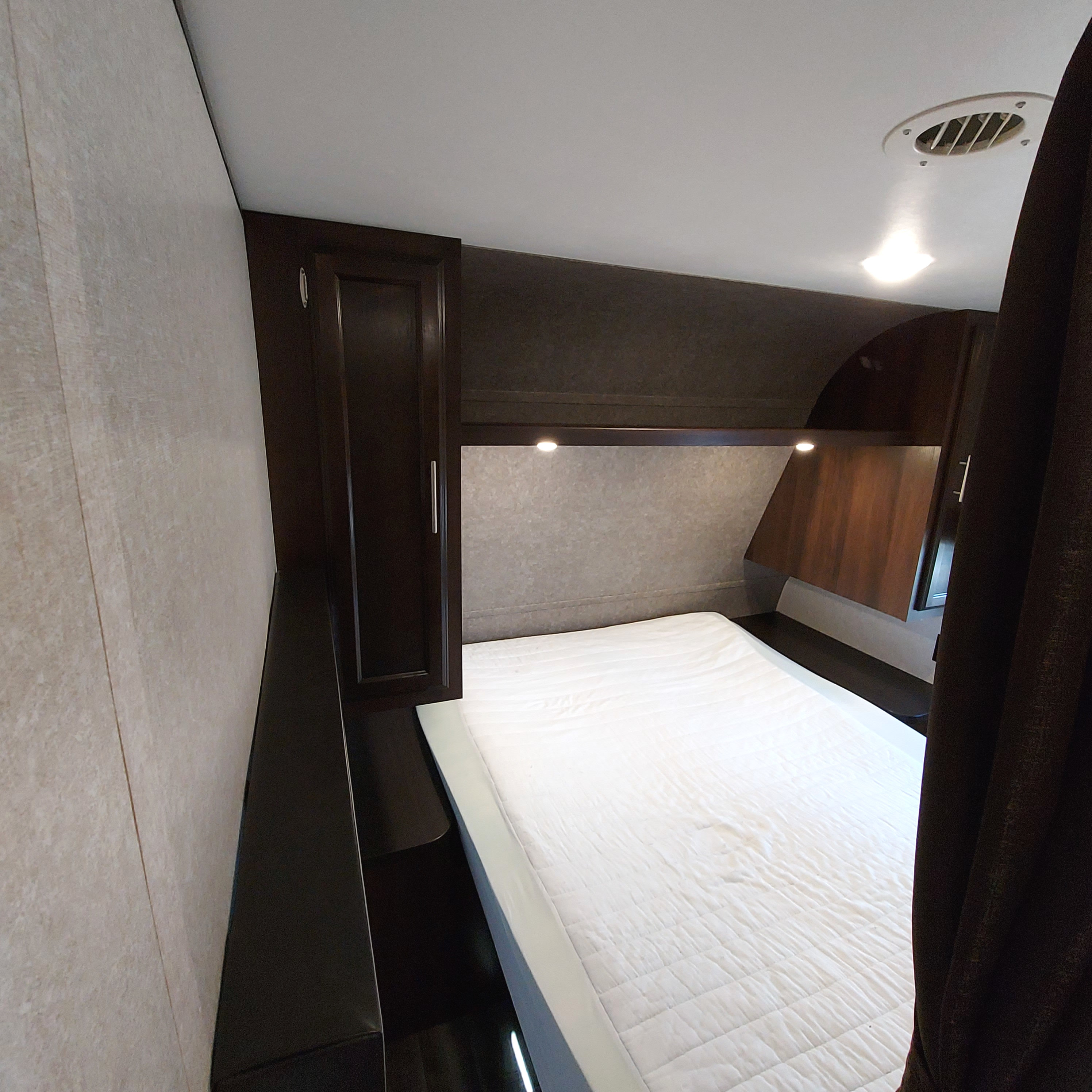 Inside an RV rental: a compact bedroom featuring a comfortable white bed, dark wood storage, and overhead lighting.. Jayco Jay Flight SLX8 2020