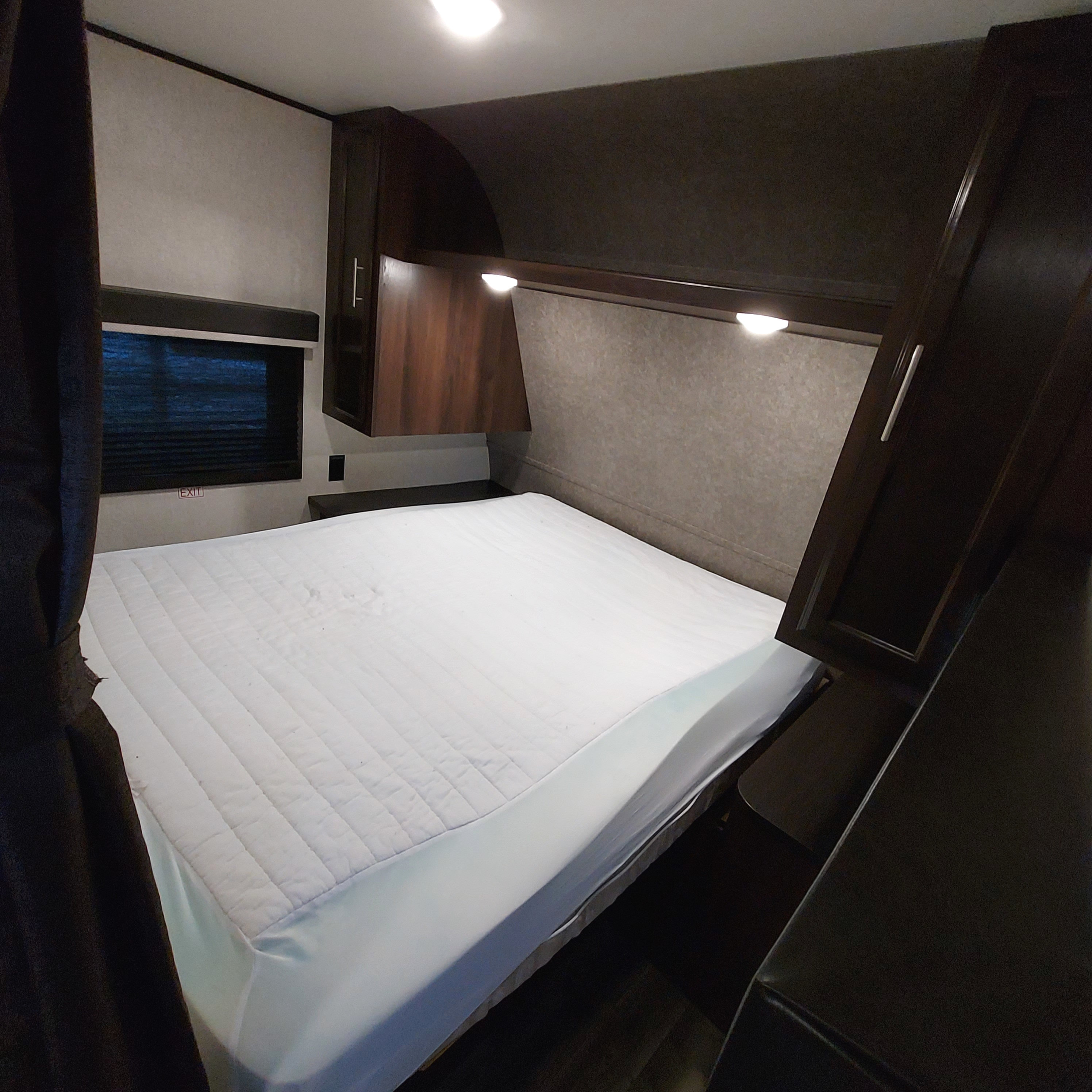 Clean RV rental bedroom features a large white mattress, dark wood cabinetry, and a window for comfortable travel.. Jayco Jay Flight SLX8 2020