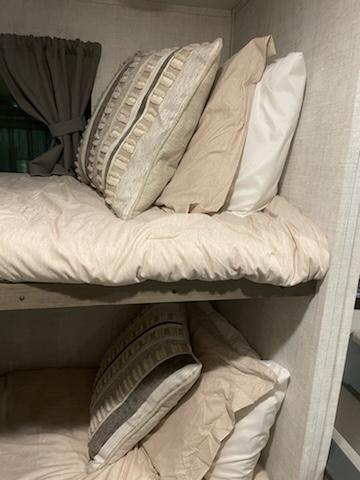 Cozy bunk beds inside an RV rental, featuring light bedding and decorative pillows, perfect for family adventures.. Gulf Stream Ameri-Lite Super Lite 2022