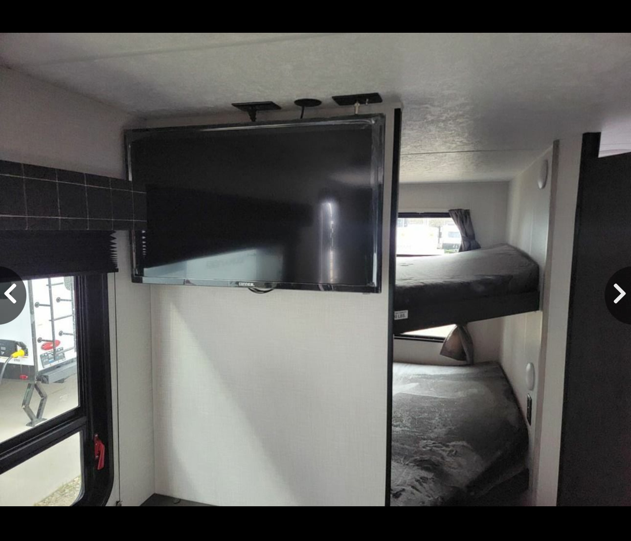 RV rental interior featuring bunk beds and a wall-mounted TV. A practical sleeping area in a travel trailer.. Sportsmen SE 2023