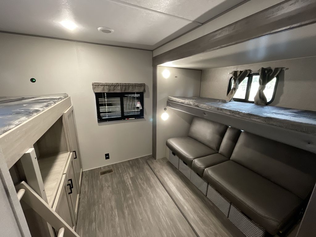 Modern RV rental bunkhouse interior with multiple bunk beds, a sofa, and built-in storage.. Forest River Aurora Aurora 2024